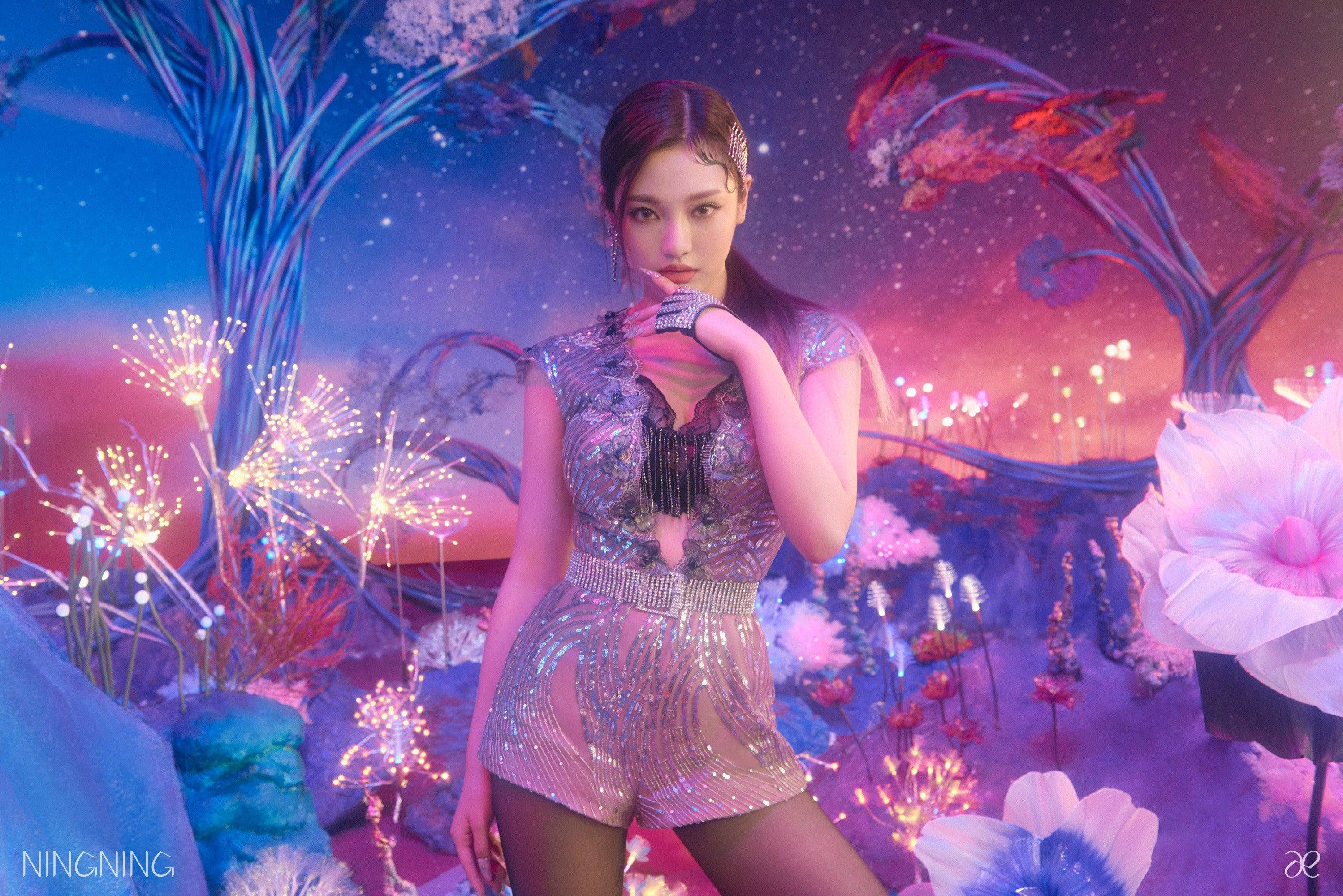 Aespa Ningning 紫色森林 壁紙 — 一位身穿閃亮銀色服裝的女性自信地站在一個超現實的宇宙花園中，周圍是發光的植物和星空。