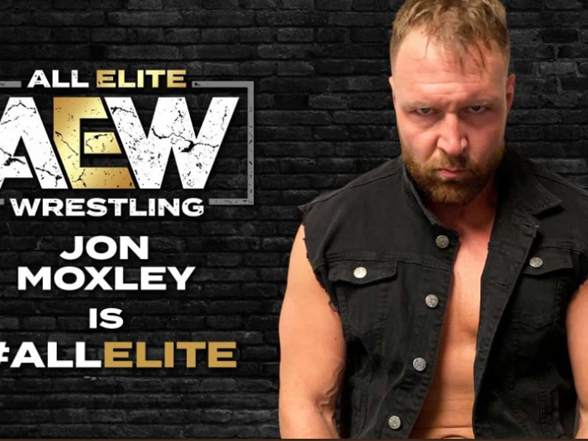 AEW 摔角巨星聯手挑戰對手 壁紙 — 摔角手 Jon Moxley 對住印有 AEW Wrestling 品牌嘅黑色磚牆，眼神銳利。