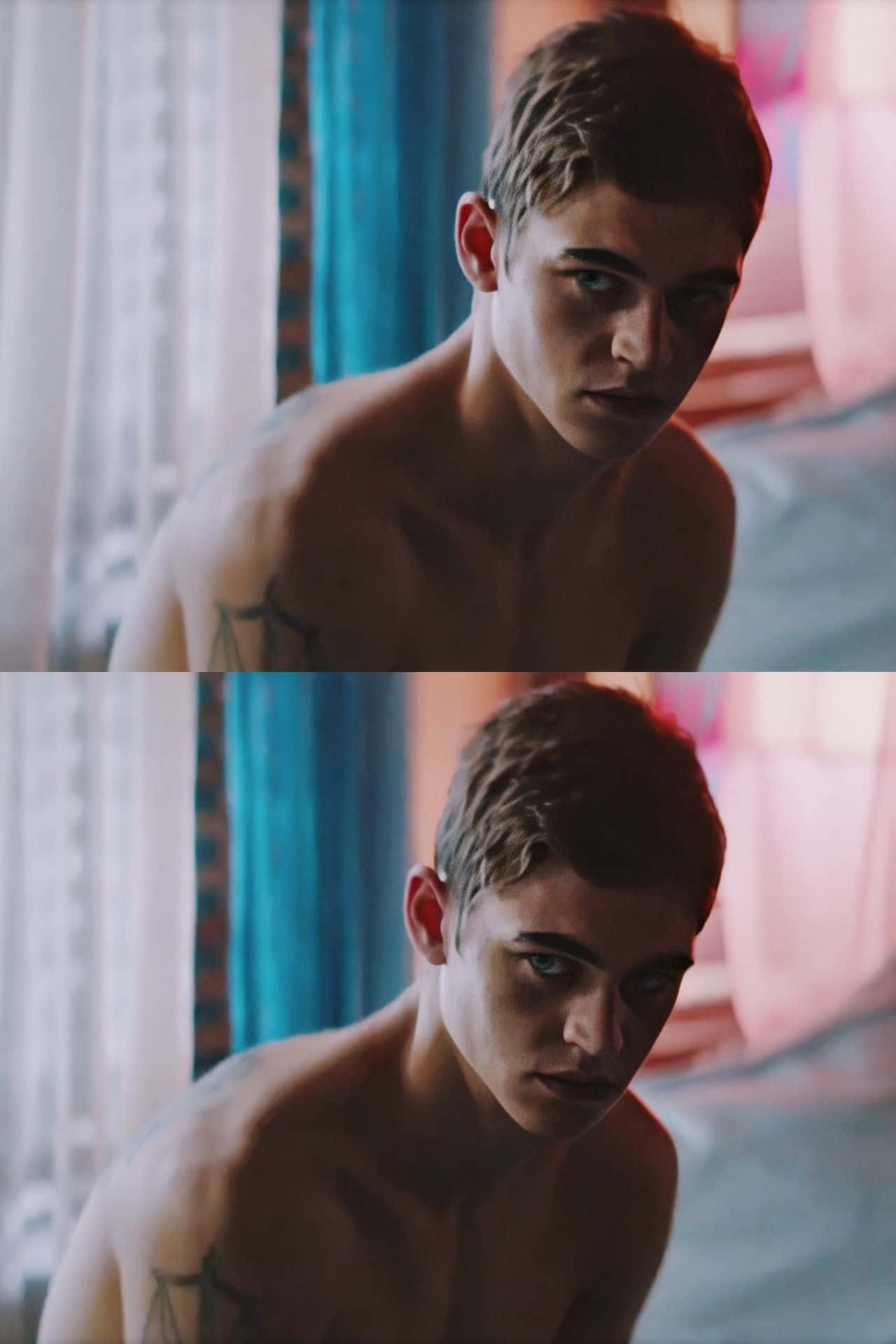 《After》系列主角 Hardin Scott 赤裸上身 壁紙 — 一位赤裸上身的年輕男子，身上有紋身，在一個光線柔和、掛著彩色窗簾的房間裡專注地凝視。
