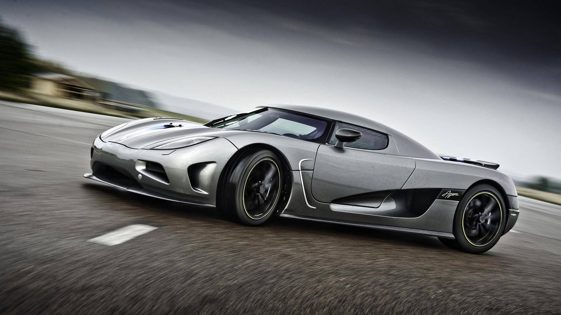 科尼賽克Agera全高清汽車壁紙 壁紙 — 一架時尚的銀色Koenigsegg Agera在陰天嘅天空下，喺一條模糊嘅瀝青路上飛馳。
