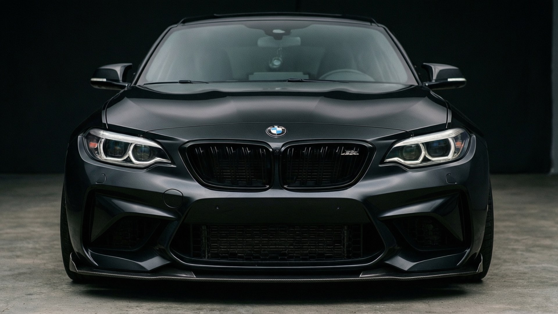 啞光黑色BMW M2跑車在攝影棚環境中的前視圖。