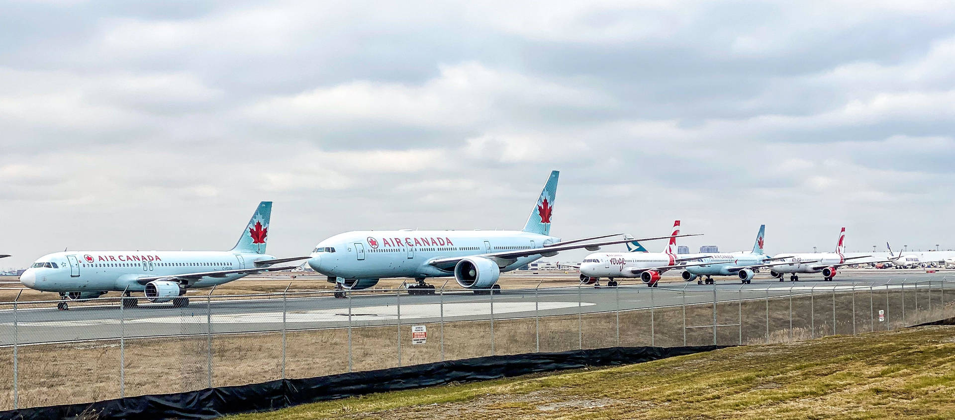 加拿大航空飛機停泊在機場停機坪，鐵絲網圍欄後方