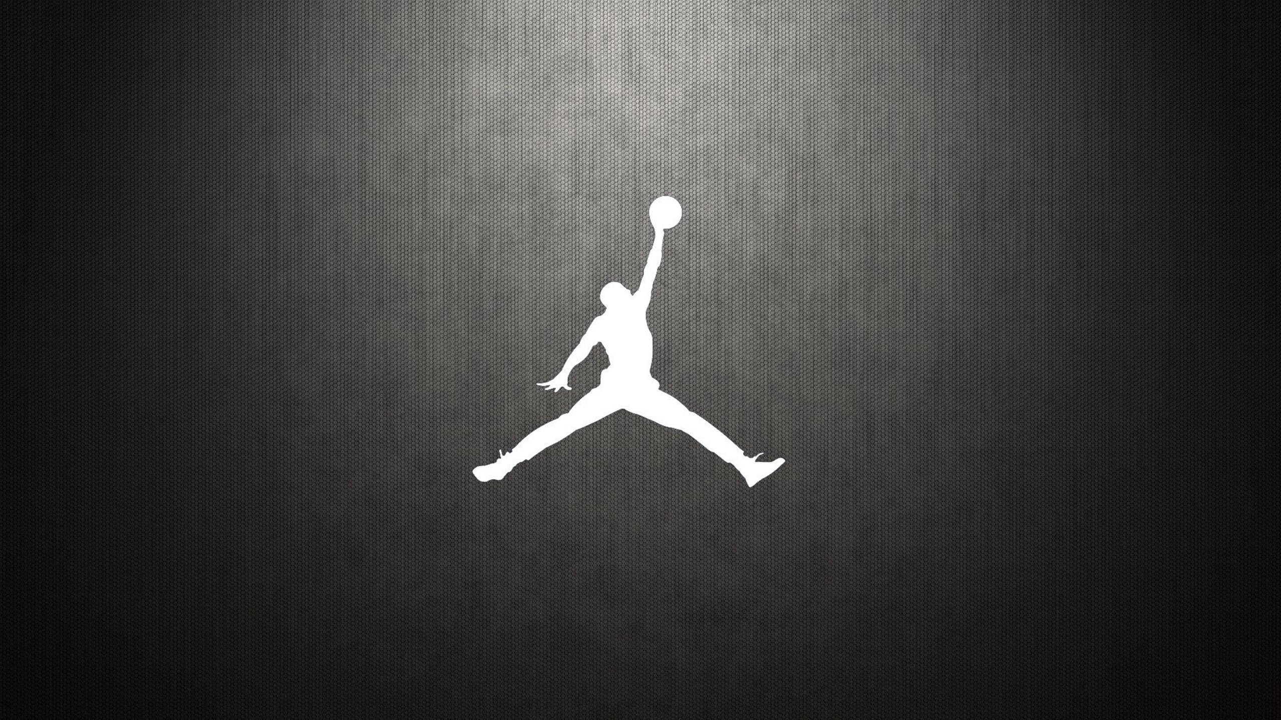 Air Jordan碳纖維圖案標誌 壁紙 — 一個鮮明的白色剪影，標誌性的Jordan標誌在紋理深灰色漸變背景上躍起。