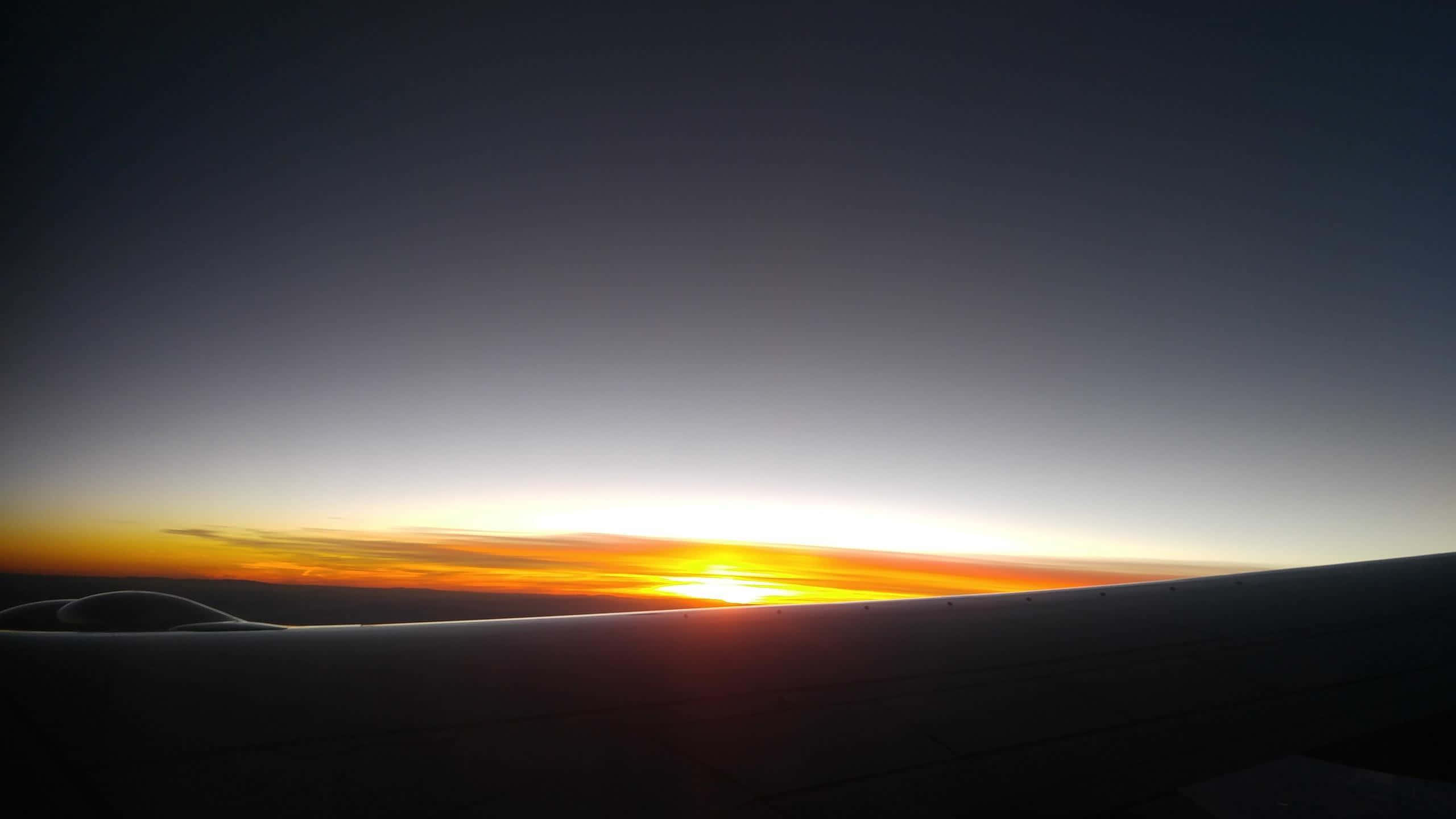 Flight 桌布 壁紙 — 飛機機翼在充滿活力的橙色和紫色日出地平線上的剪影。
