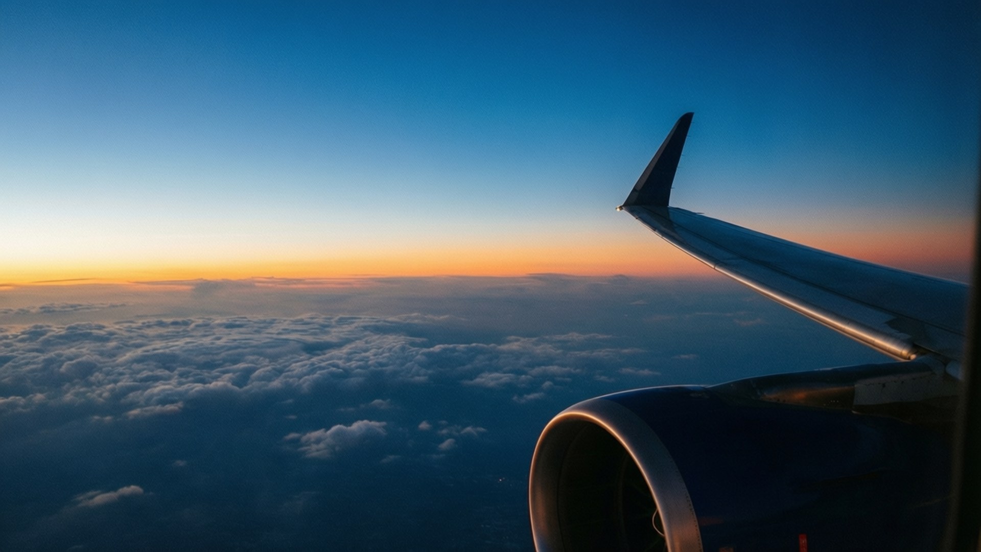 日出時從窗戶俯瞰雲層上的飛機機翼和引擎
