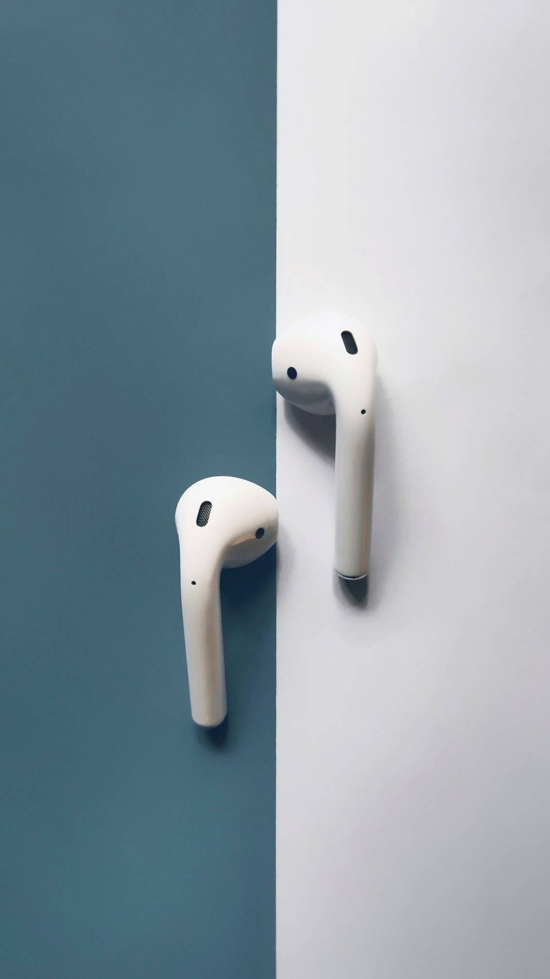 藍灰背景的白色藍牙AirPods 壁紙 — 兩個白色無線耳塞靠著一分為二的青綠色和白色背景，呈現極簡構圖。