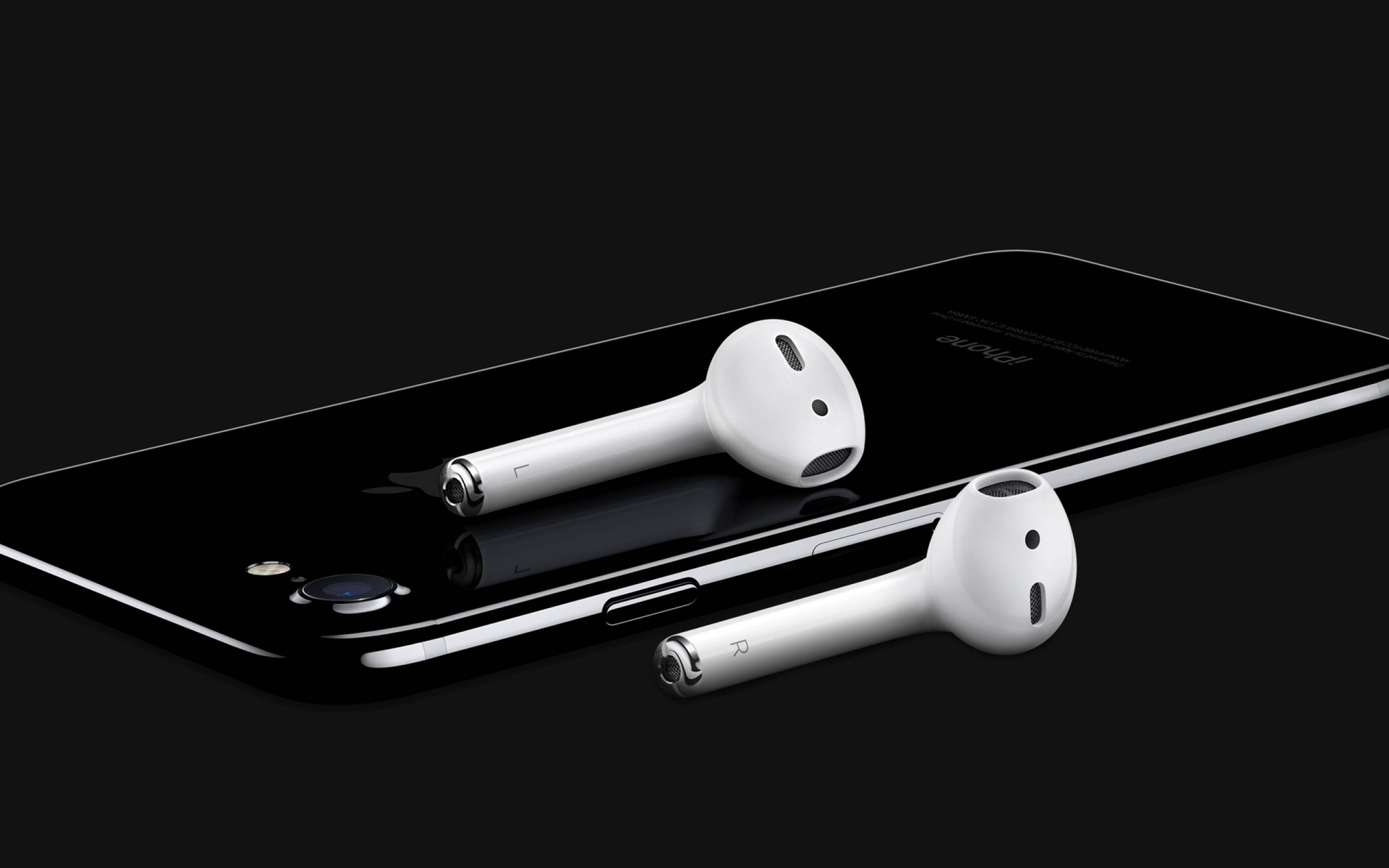 AirPods 與黑色 iPhone SE 壁紙 — 白色無線耳塞優雅地放置在時尚的黑色智能手機上，背景為深色。