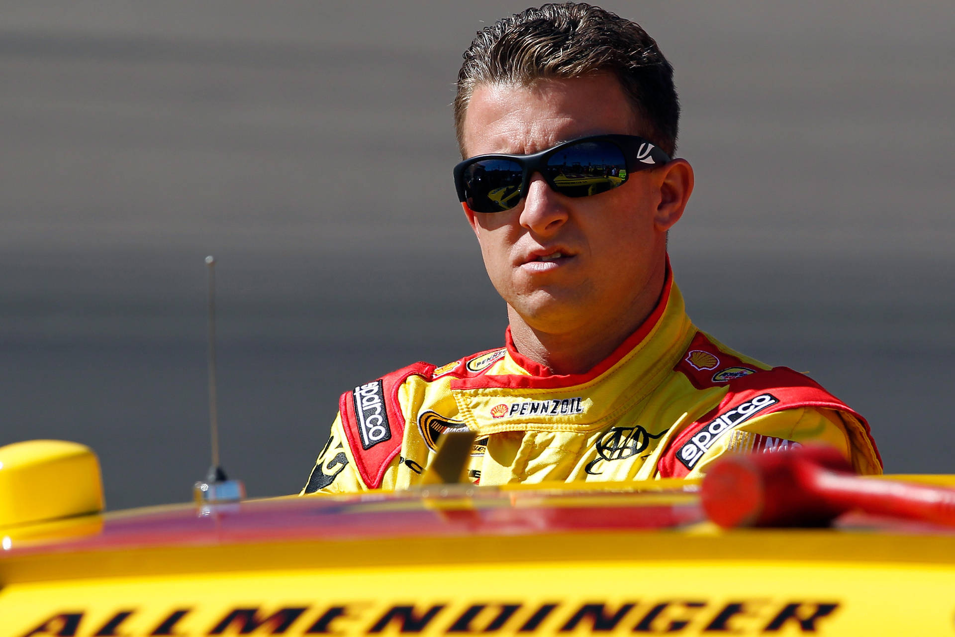 穿著賽車裝備的NASCAR車手從他的黃色賽車中探出身子。