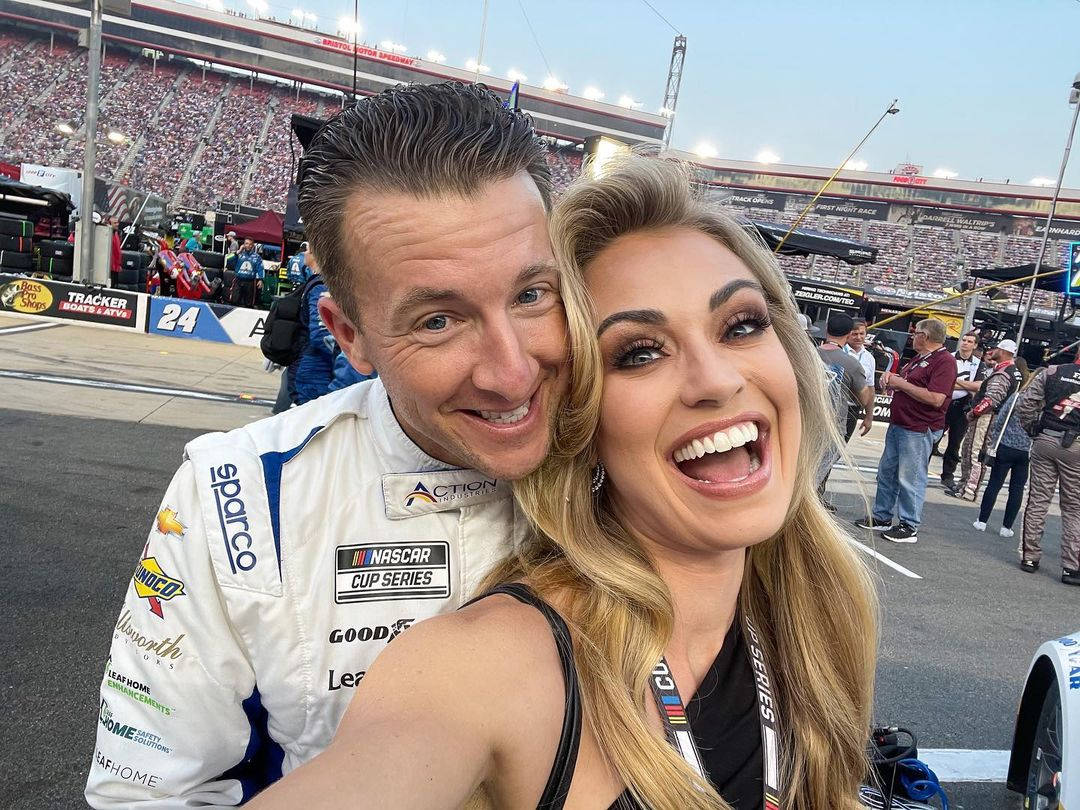 NASCAR車手和女子在賽車場活動中微笑