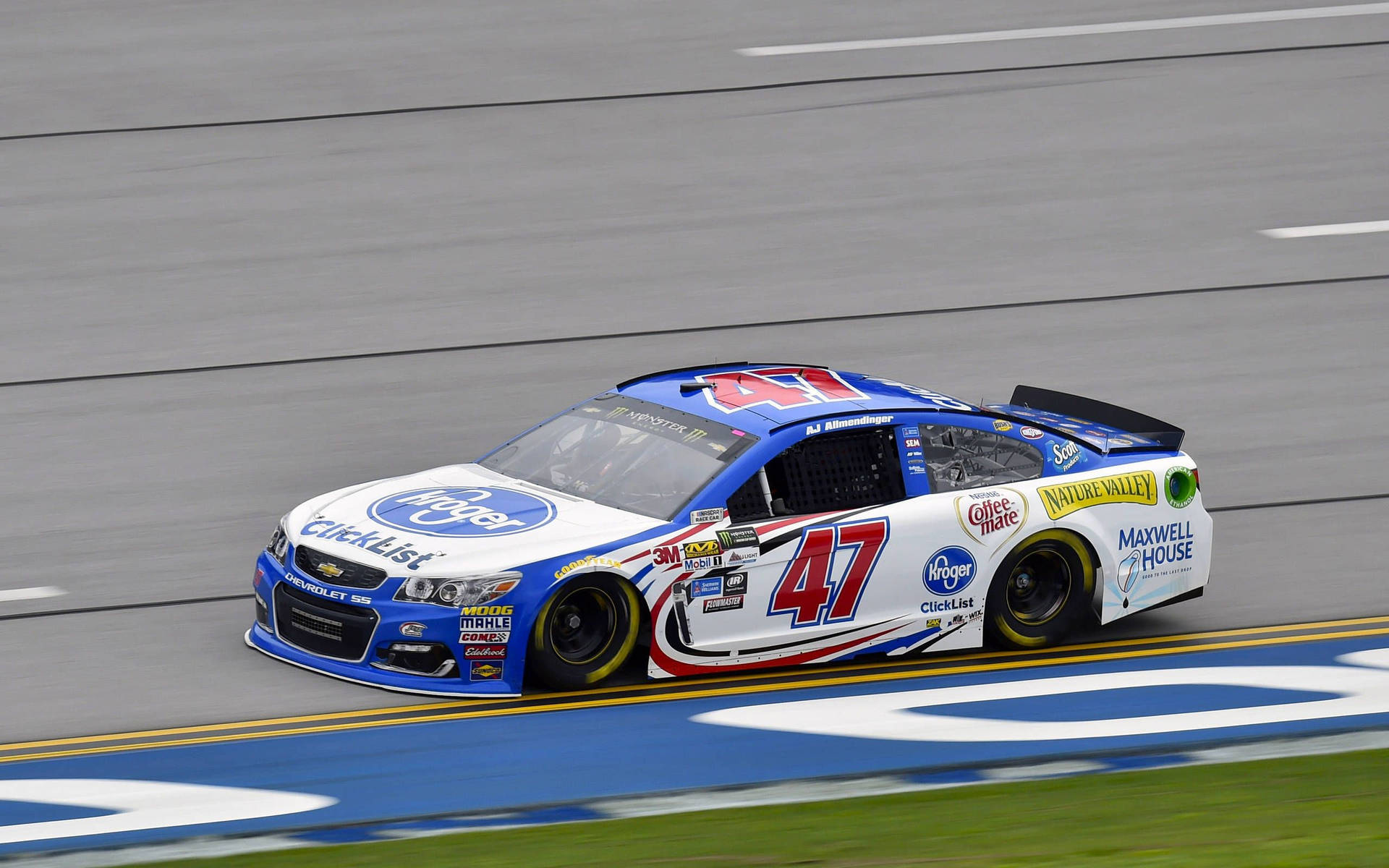 AJ Allmendinger 賽道上 壁紙 — 一輛藍白相間的 #47 雪佛蘭 NASCAR 賽車在賽道上疾馳，背景是模糊的瀝青和草地。