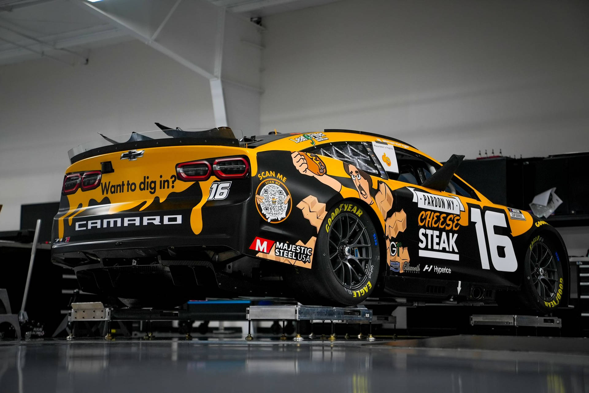 車庫內帶有芝士牛排廣告的黑黃色NASCAR賽車。