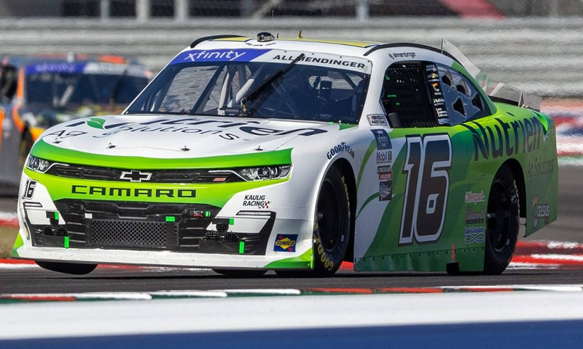 日間比賽中，綠色和白色的 NASCAR 賽車 16 號在賽道上奔馳。