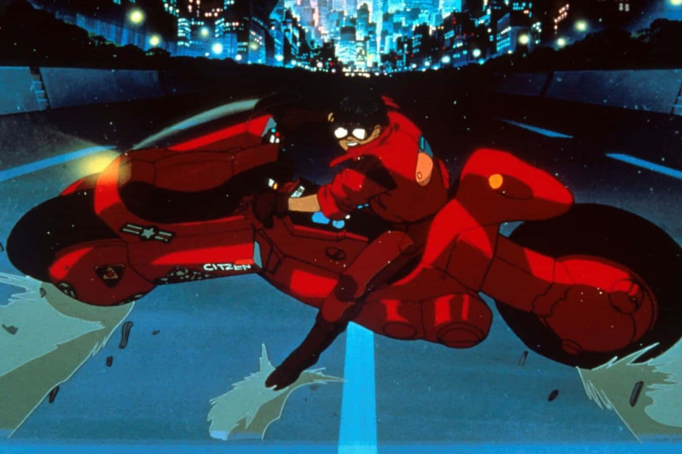 Akira 代表藝術畫 壁紙 — 一名身穿紅色賽車服的紅色電單車手在夜間穿過霓虹燈閃爍的城市景觀，背景是高聳發光的摩天大樓。