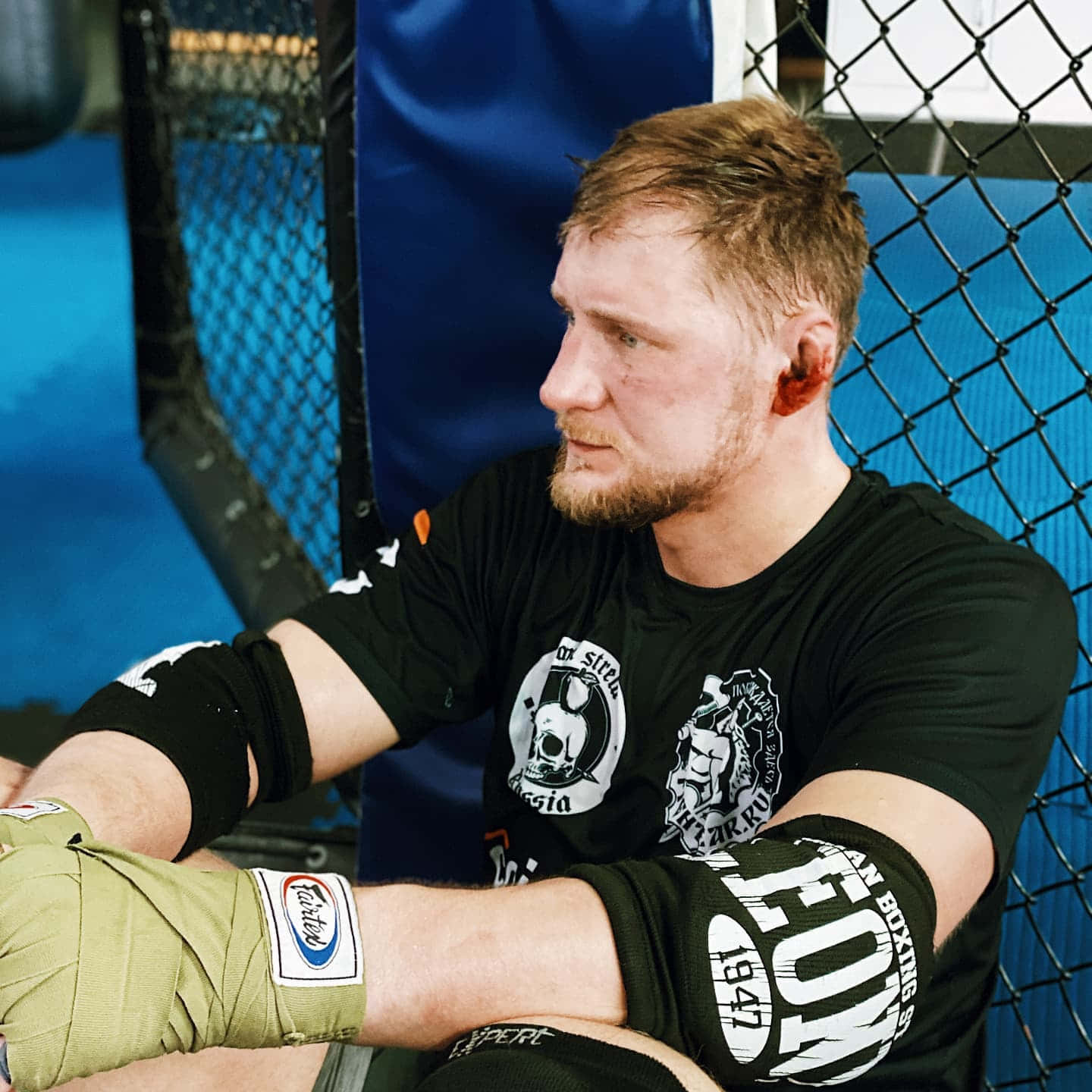 纏著繃帶的MMA拳手在藍色籠內休息。