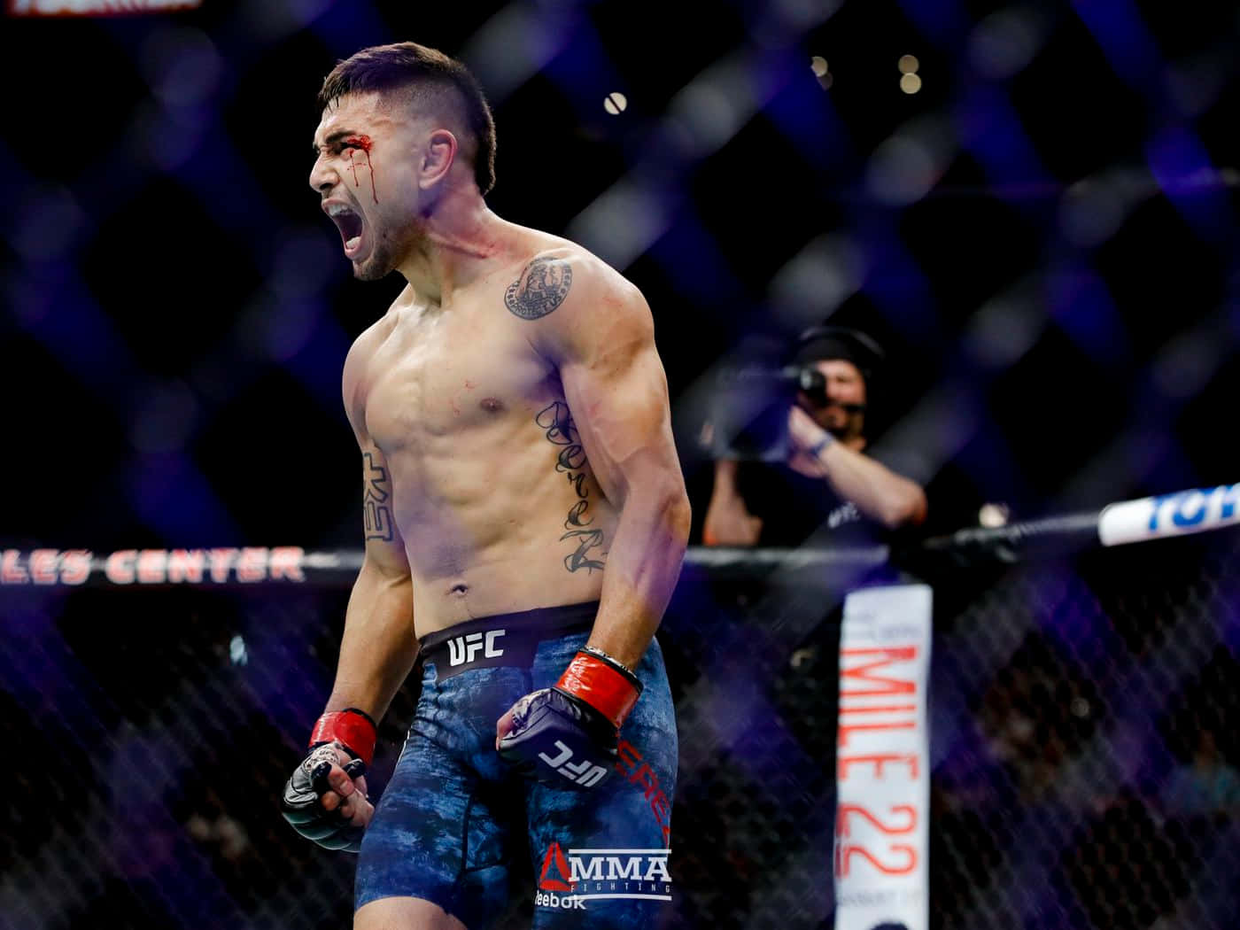 MMA拳手在八角籠內滿臉鮮血慶祝勝利。