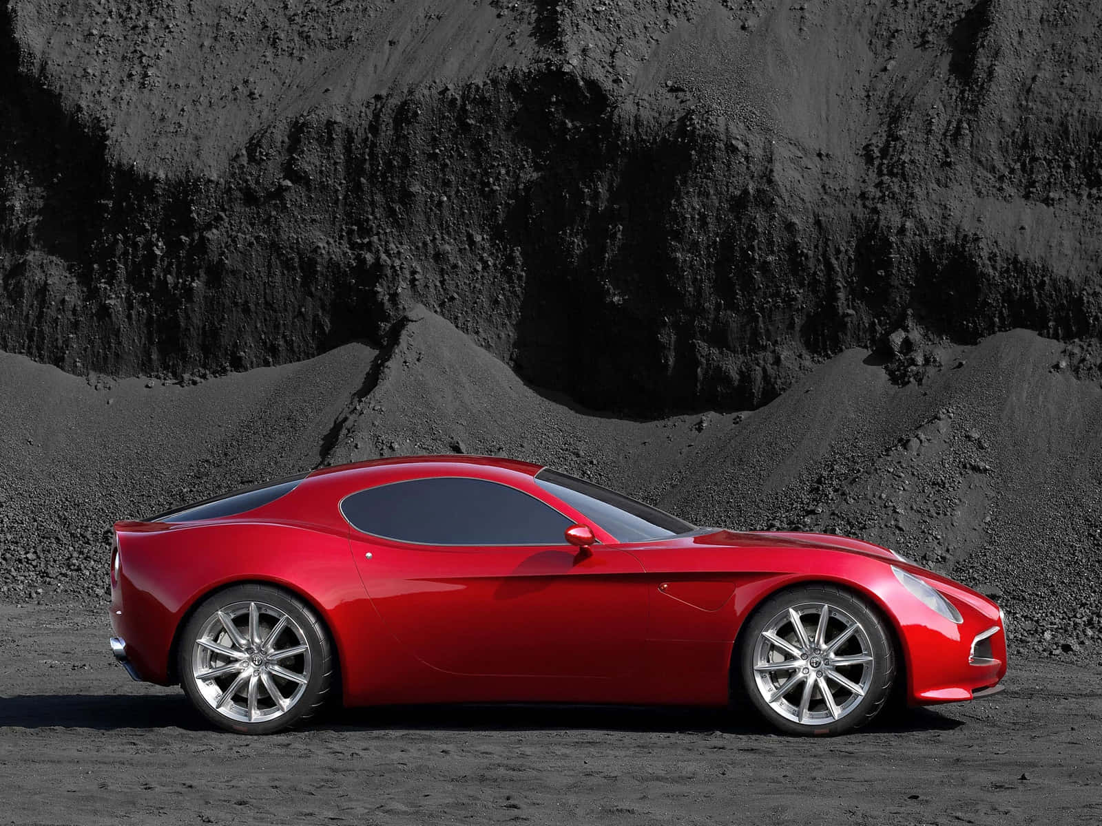Alfa Romeo 8C Competizione — 美與性能的完美結合 壁紙 — 一輛光亮的紅色跑車在明亮的日光下，在黑色火山岩背景下閃閃發光。