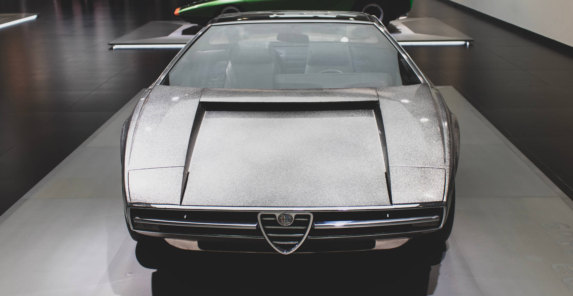 銀色 Alfa Romeo 概念車在博物館中展示，地板具有反射效果。