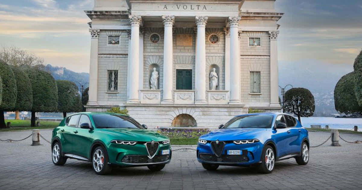 兩輛Alfa Romeo SUV停在經典別墅前，別墅有雕像和修剪整齊的樹籬。