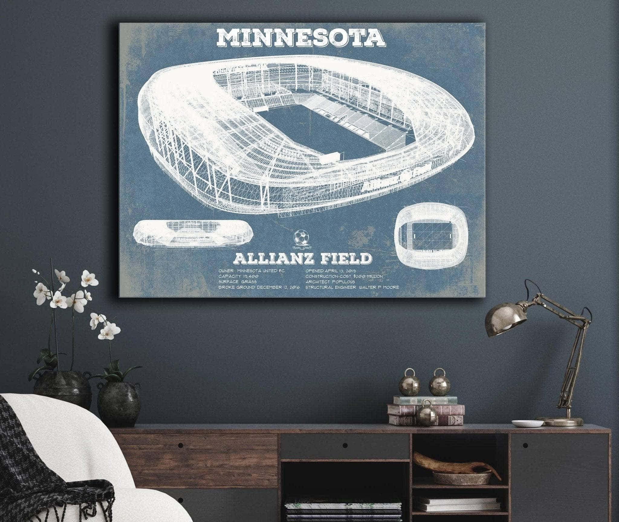 明尼蘇達聯隊主場Allianz Field壯觀景觀 壁紙 — 一幅明尼蘇達州安聯球場的藍圖風格畫布掛在深色牆上，下方是木製矮櫃，上面有燈和白色蘭花。