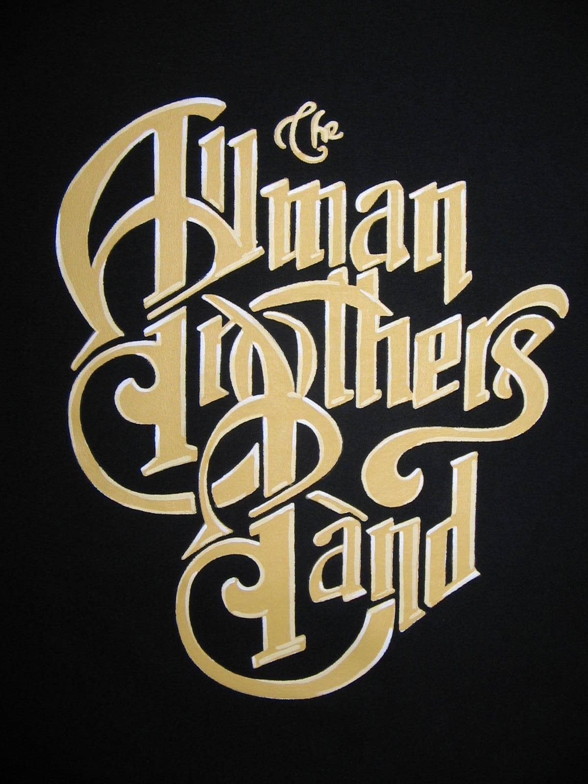 Allman Brothers Band 歌曲 Good Clean Fun 壁紙 — The Allman Brothers Band 的金色華麗字體在純黑色背景上發光。