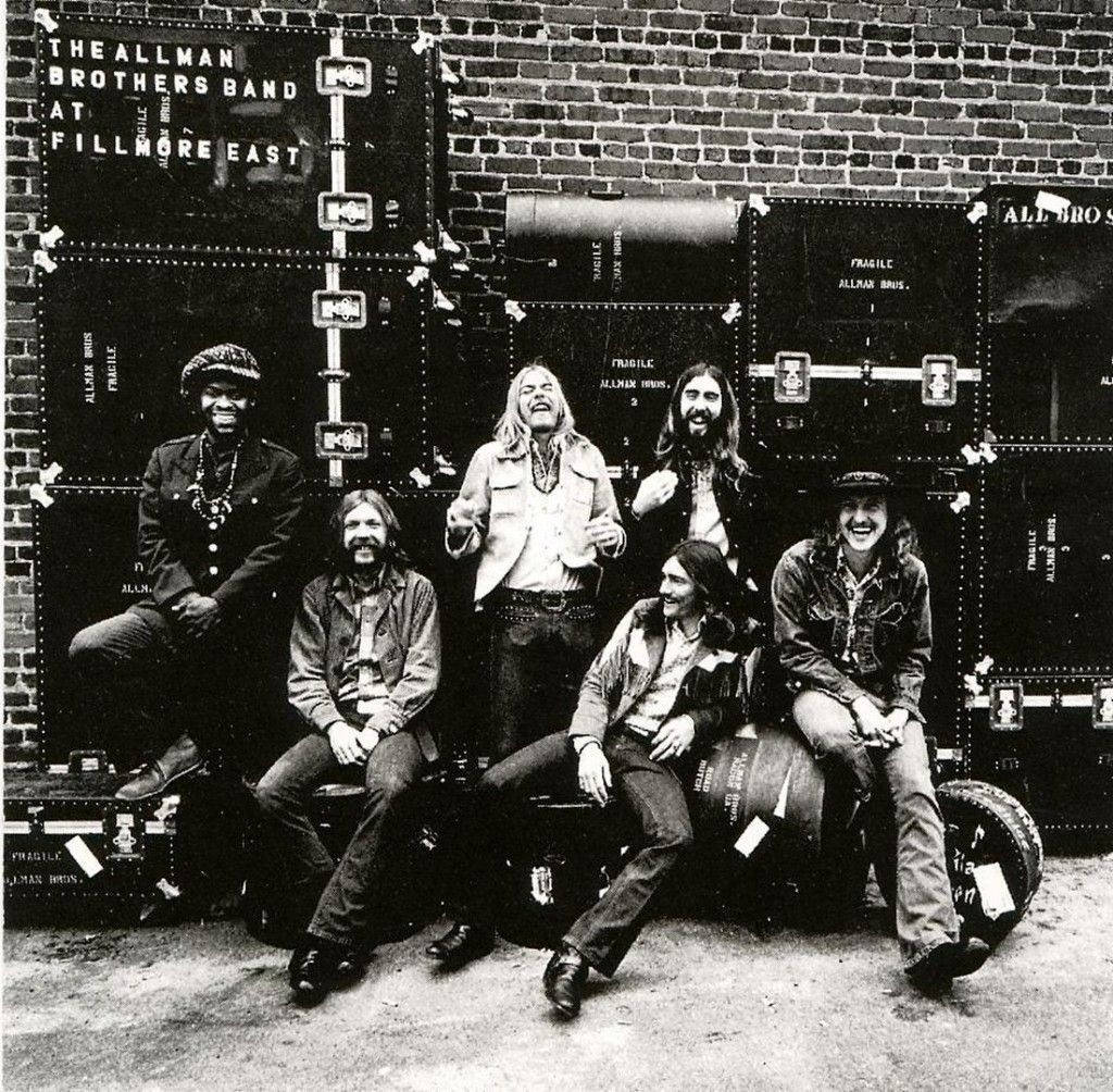 Allman Brothers Band 六人合照 壁紙 — The Allman Brothers Band 喺磚牆前面，喺佢哋有標籤嘅設備箱前面開心咁擺甫士。