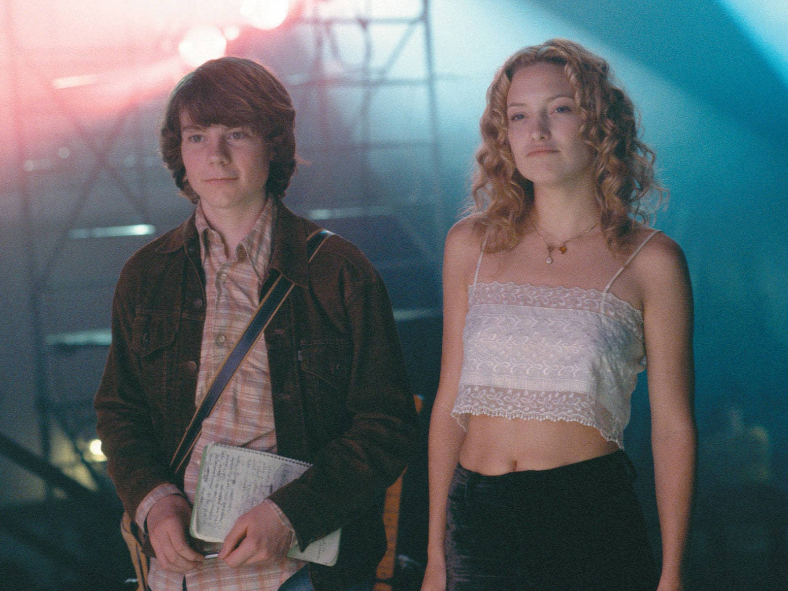 《 Almost Famous 》凱特·哈德森與帕特里克·富吉特 壁紙 — 兩個年輕人站在色彩繽紛的舞台燈光下，背後有金屬桁架結構。