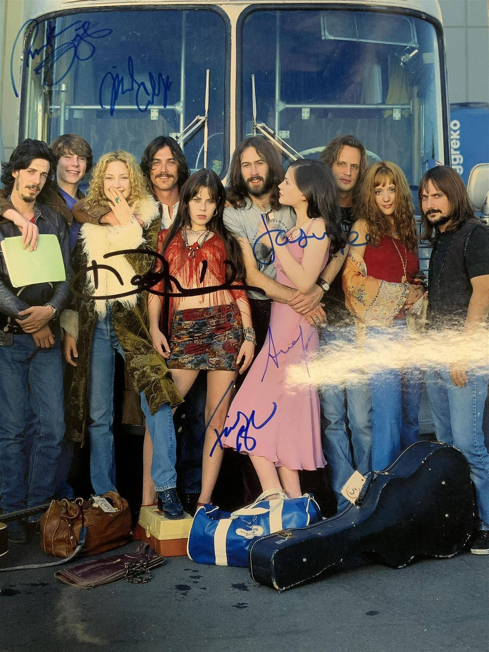 《 Almost Famous 》演員合照 壁紙 — 一張樂隊Fleetwood Mac在旅遊巴士前擺姿勢的簽名照片，穿著70年代復古服裝和音樂裝備。