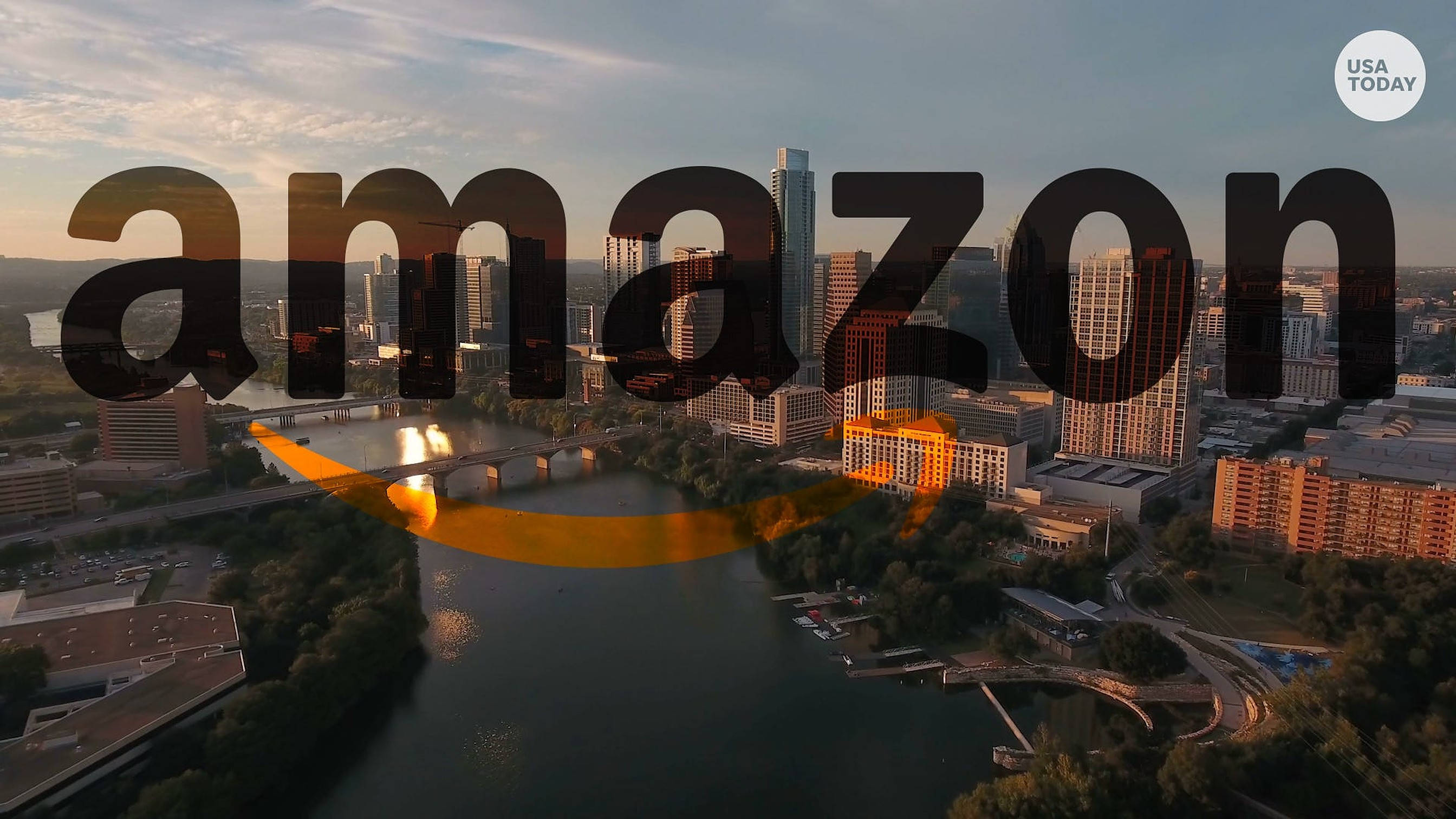 Amazon 標誌與城市 壁紙 — 日落時分城市天際線的鳥瞰圖，亞馬遜標誌疊加在河流和橋樑之上。