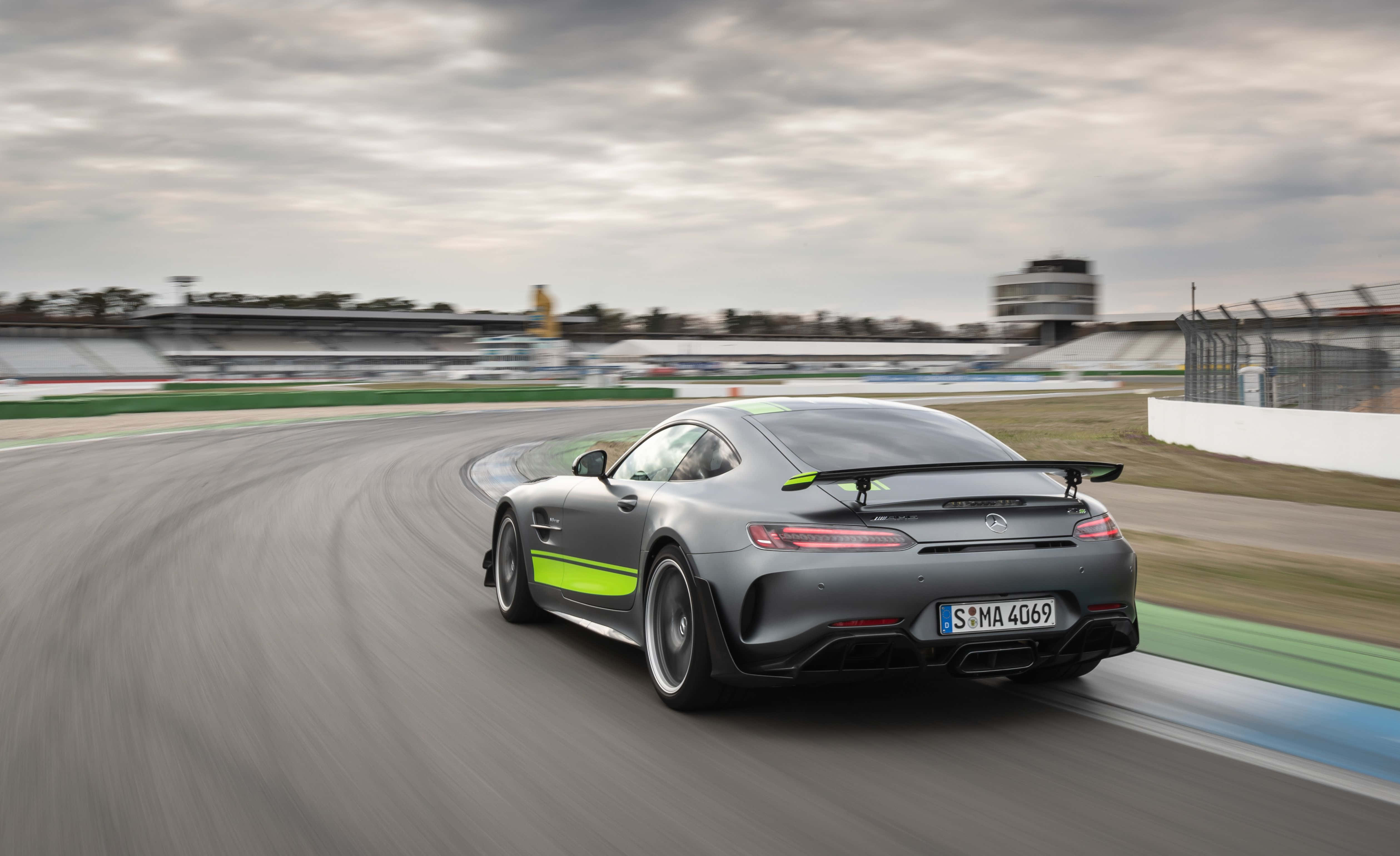 黑色梅賽德斯-AMG GT R Pro賽車競速背景 壁紙 — 一輛時尚的灰色Mercedes-AMG GT R，帶有螢光綠色點綴，在陰天潮濕的賽道上奔馳。