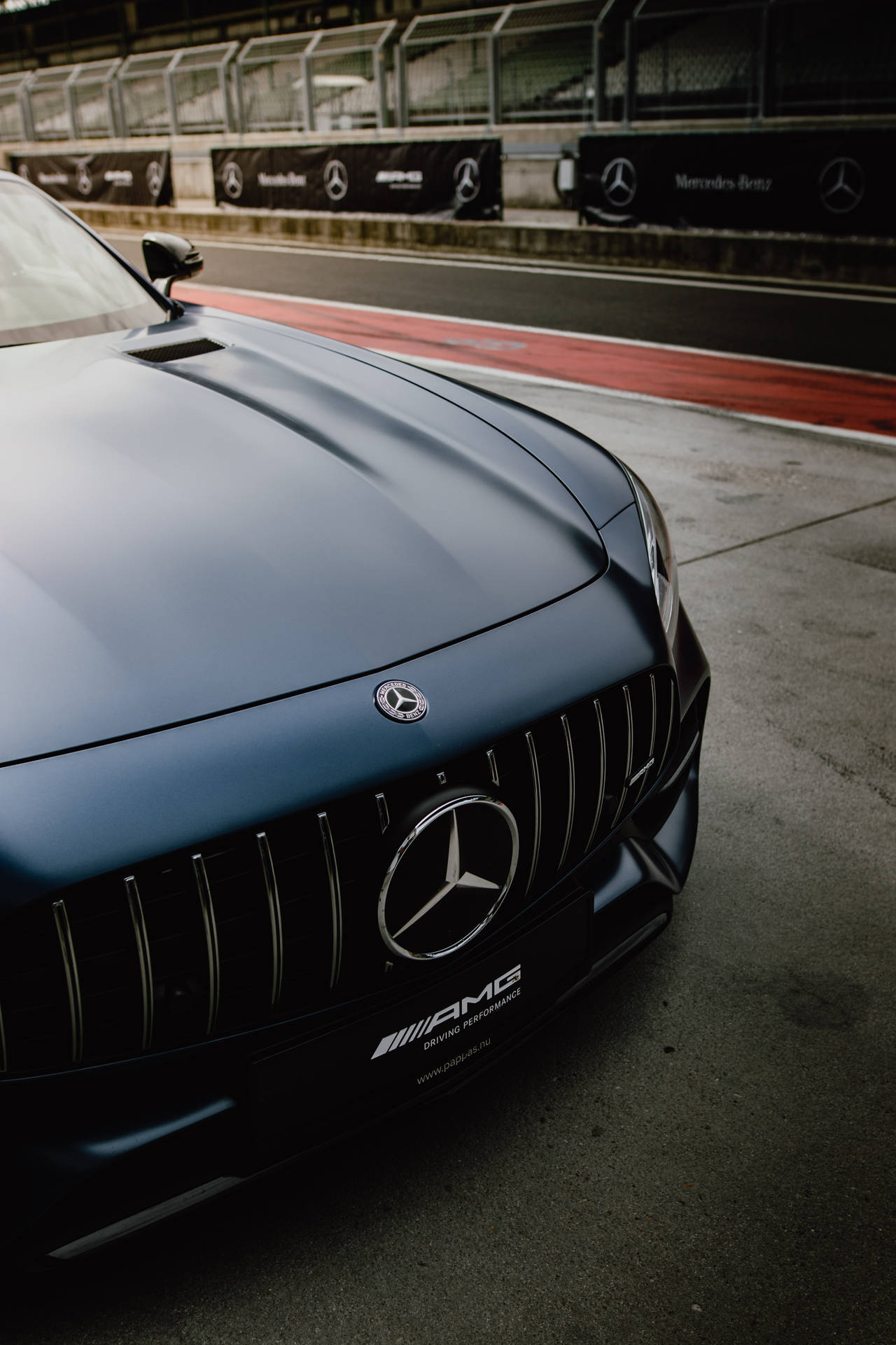 啞光藍色 Mercedes-AMG 跑車在賽車場上，帶有紅色路緣。