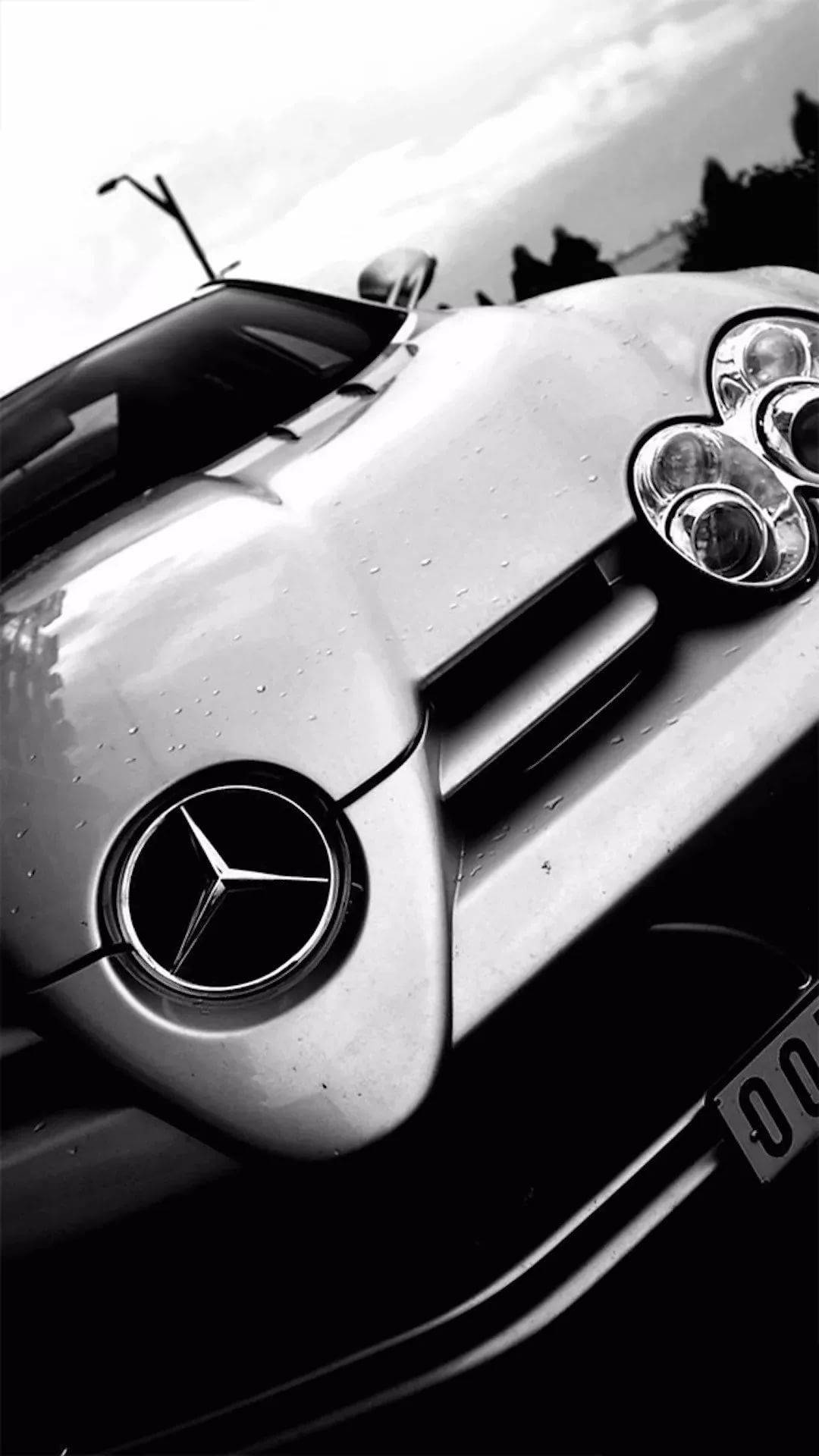 白色梅賽德斯-AMG 車標 iPhone 壁紙 — 一輛流線型梅賽德斯跑車彎曲引擎蓋上閃爍著雨滴的黑白特寫。