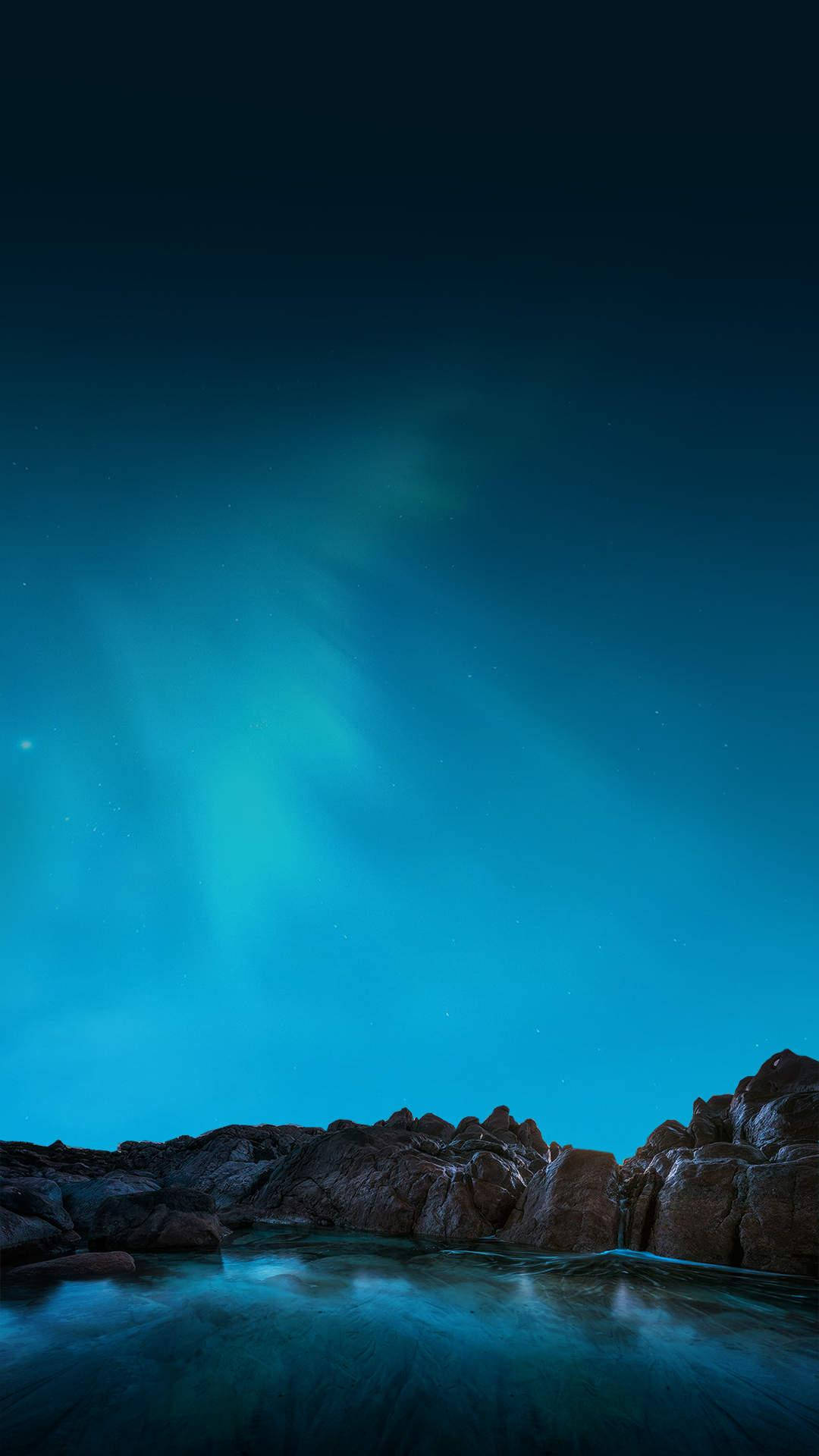 超AMOLED極光 壁紙 — 北極光在繁星點點的夜空下，在岩石海岸線上舞動著充滿活力的青綠色。