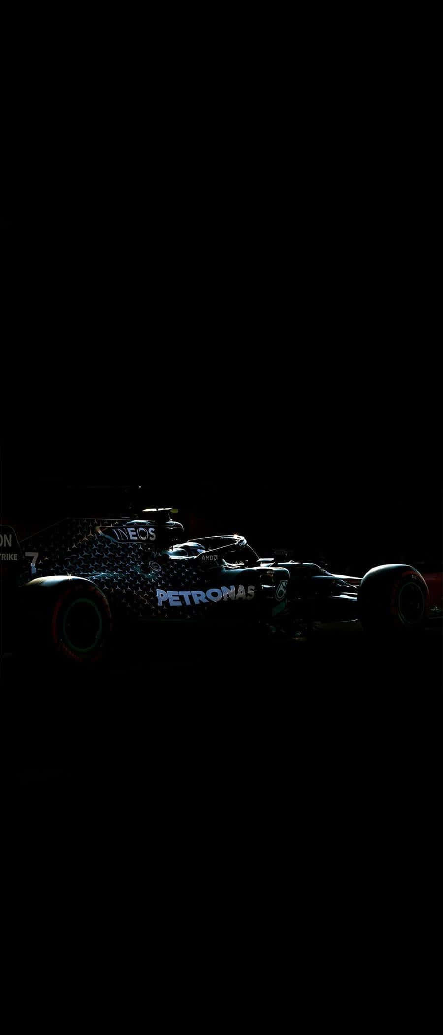 AMOLED S梅賽德斯AMG Petronas F1賽車 壁紙 — 一輛流線型一級方程式賽車在漆黑背景下，於戲劇性的低光中閃耀著贊助商標誌。