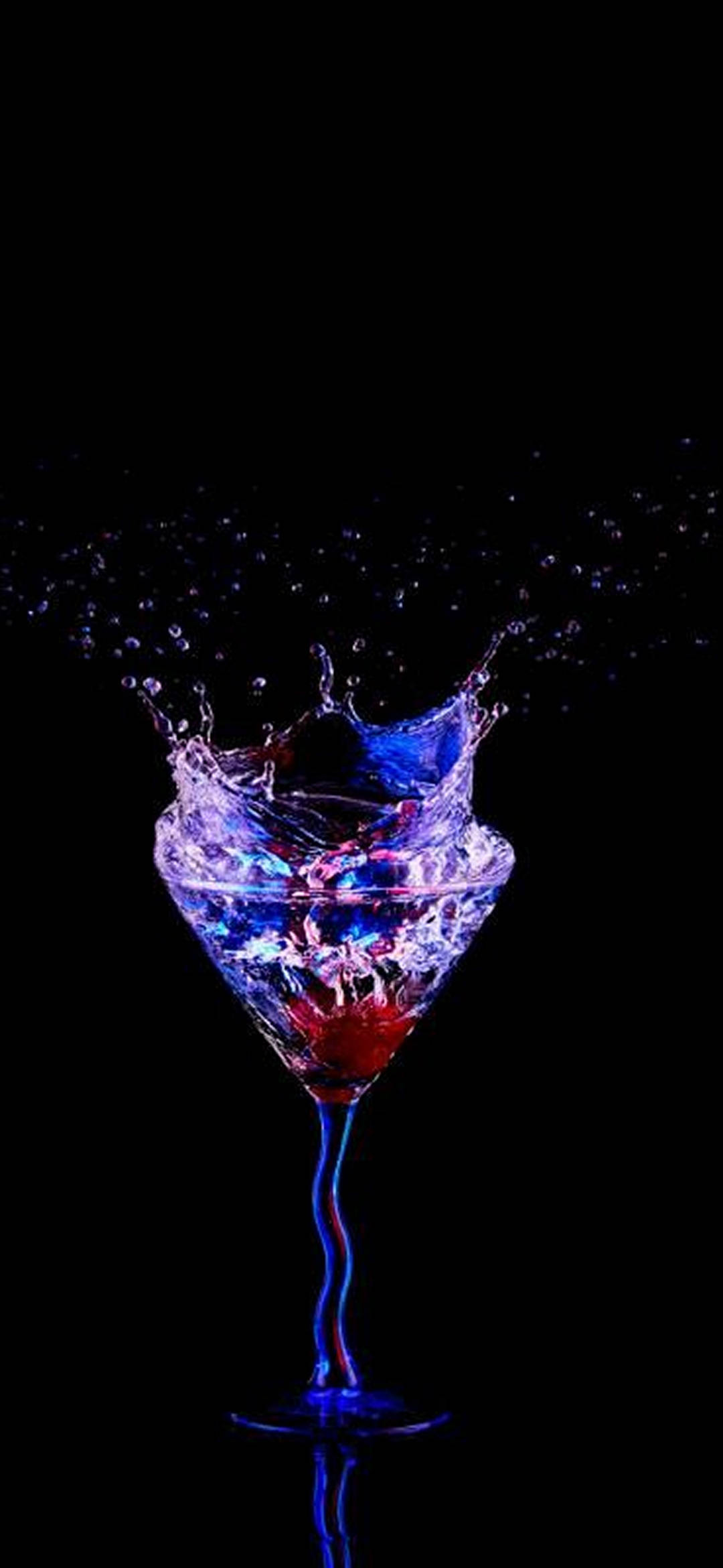 AMOLED 馬格麗塔雞尾酒杯 壁紙 — 一個裝滿鮮豔藍色和紅色液體的马提尼杯在純黑色背景上爆發出閃閃發光的水花。