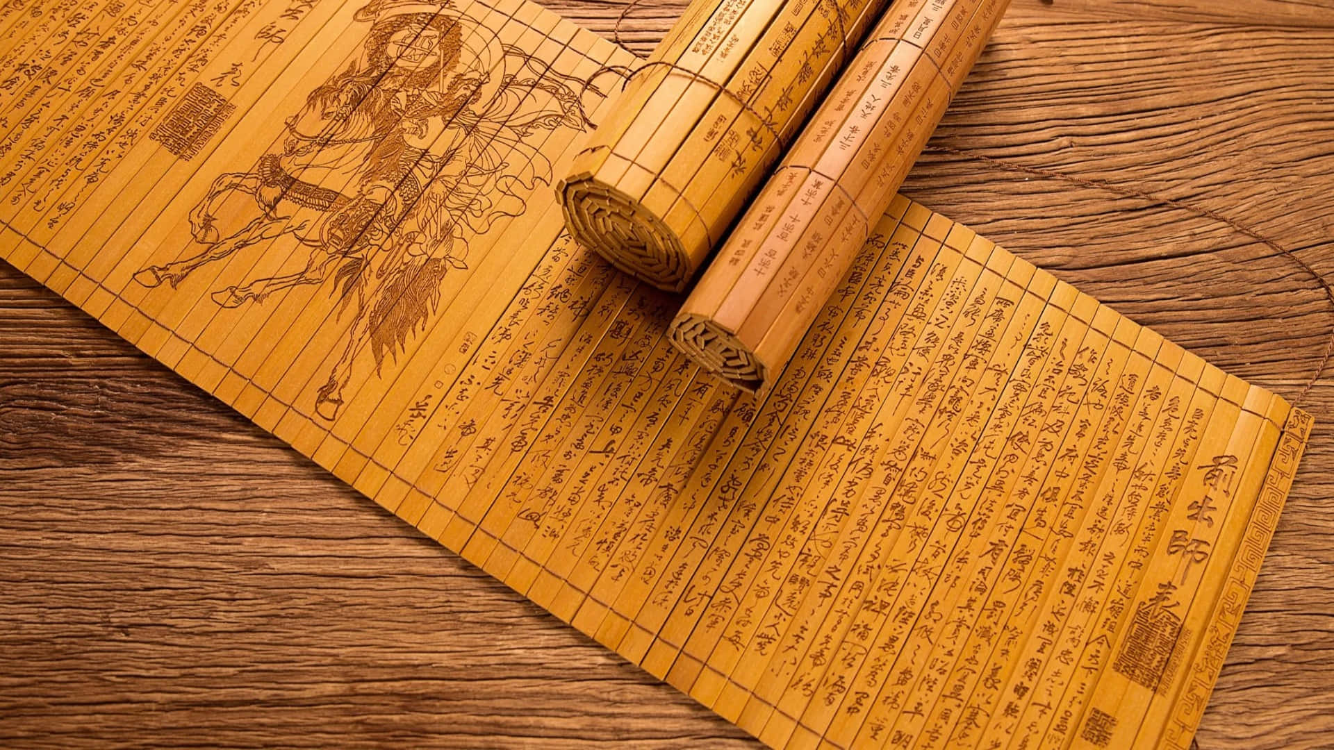  壁紙 — 古老的竹簡上刻有精細的書法和戰士插圖，放置在質樸的木質表面上。
