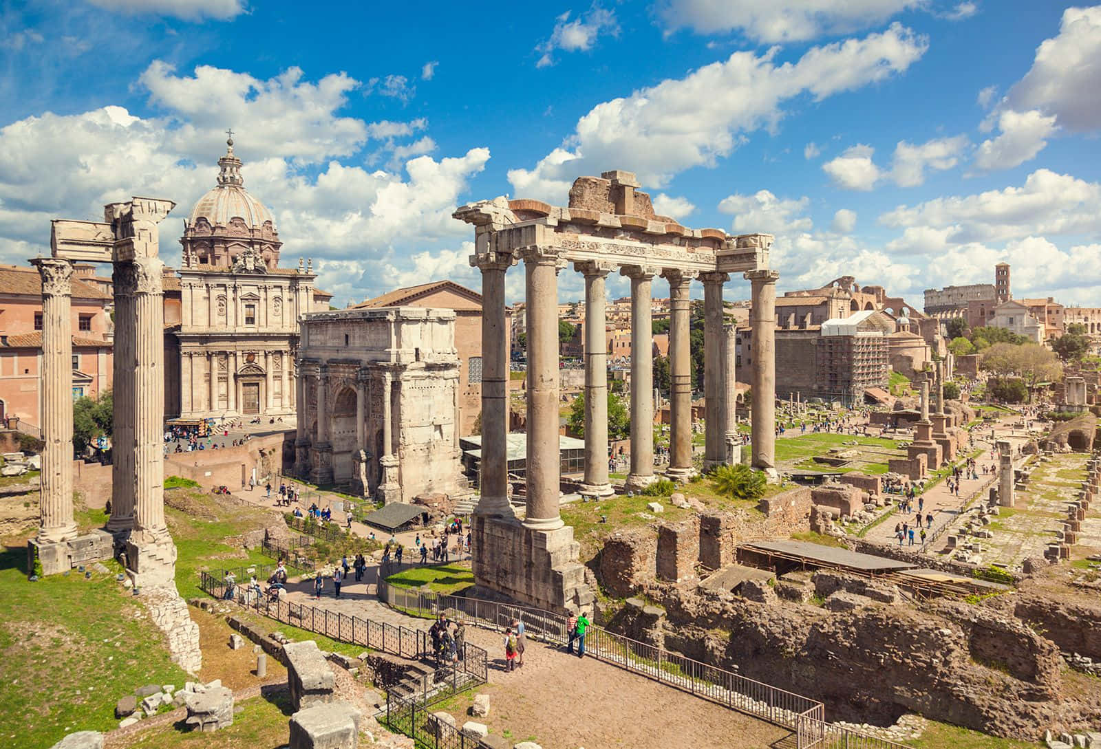 Roman 桌布 壁紙 — 古羅馬遺跡，有高聳的柱子和圓頂建築，在明亮的藍天下有蓬鬆的雲朵。