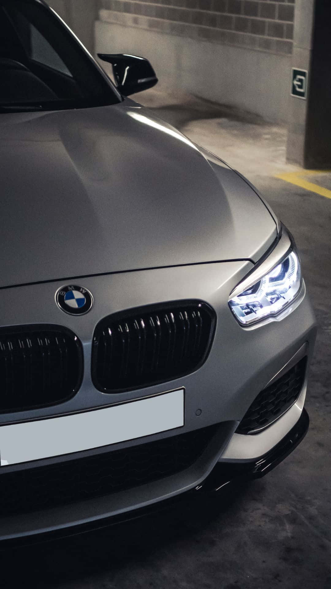 Android BMW 融合機械力量與 Android 的靈活 壁紙 — 一輛時尚的銀色寶馬跑車，車頭燈閃爍，停泊在光線昏暗的地下停車場。