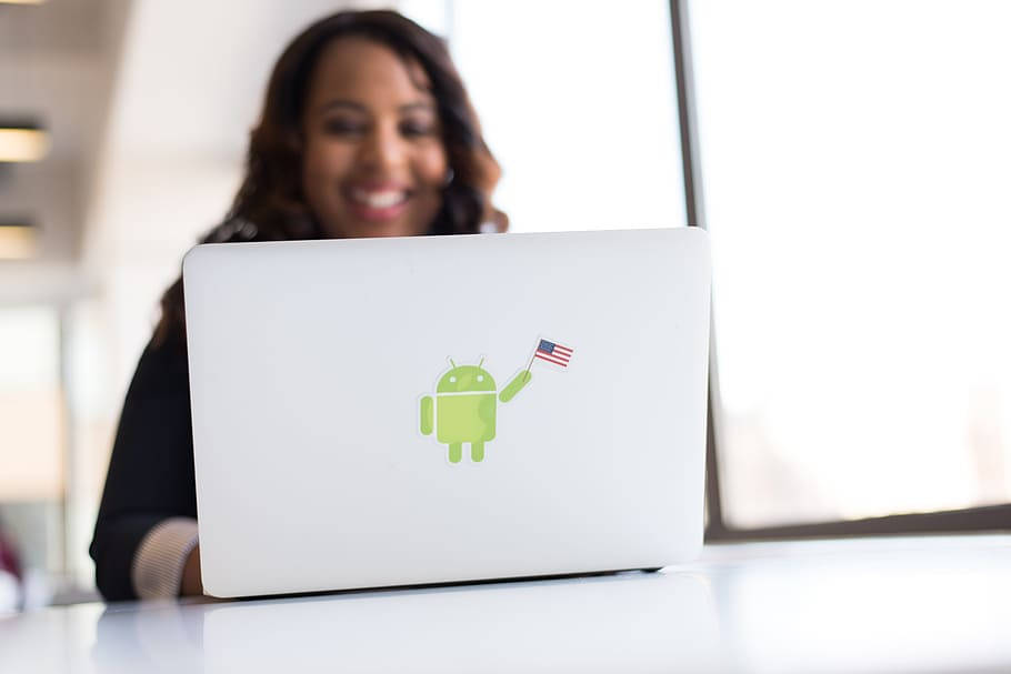 女性在手提電腦後微笑，Android吉祥物手持美國國旗貼紙。