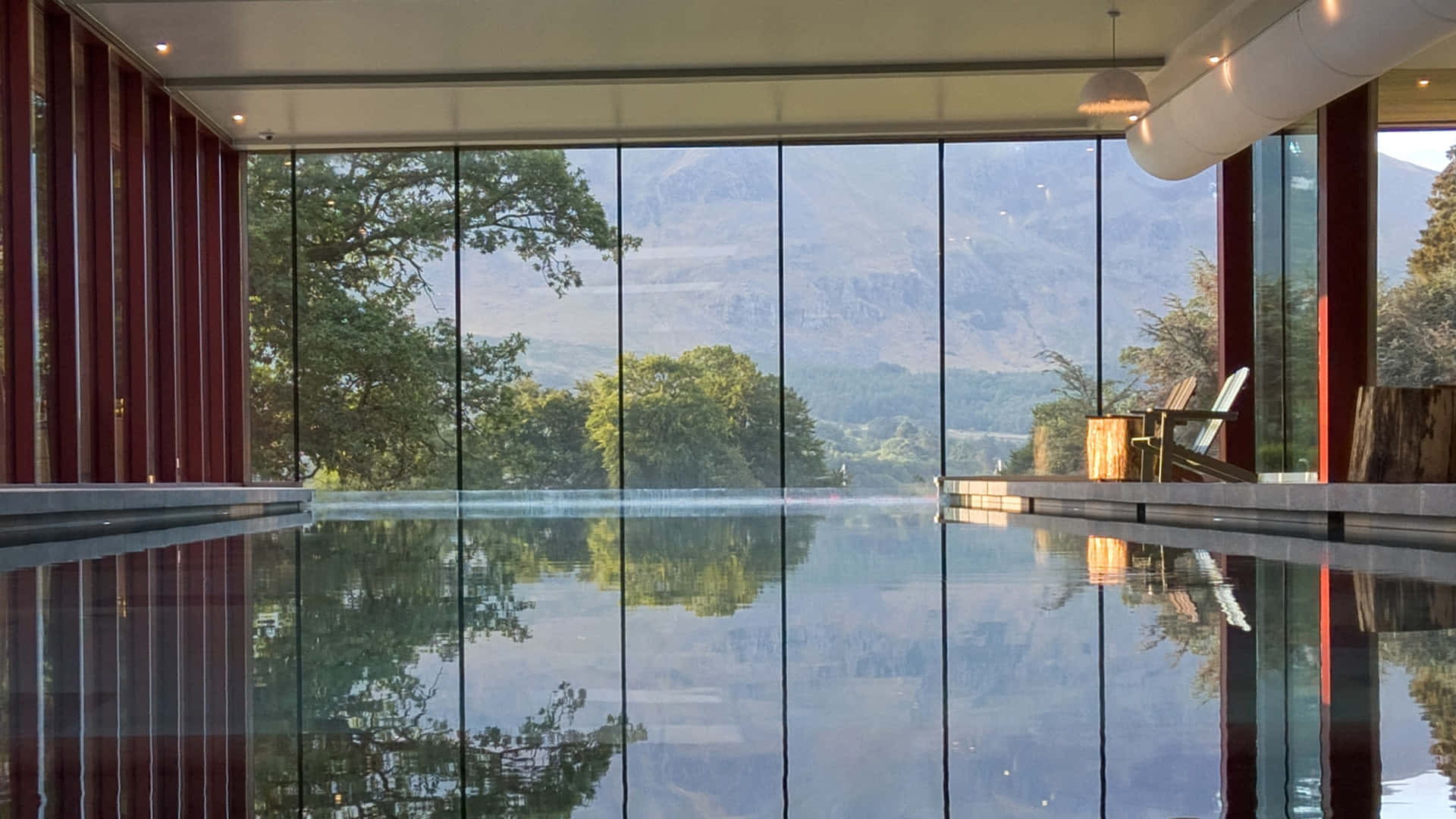 現代室內泳池，玻璃牆映照山巒和樹木。