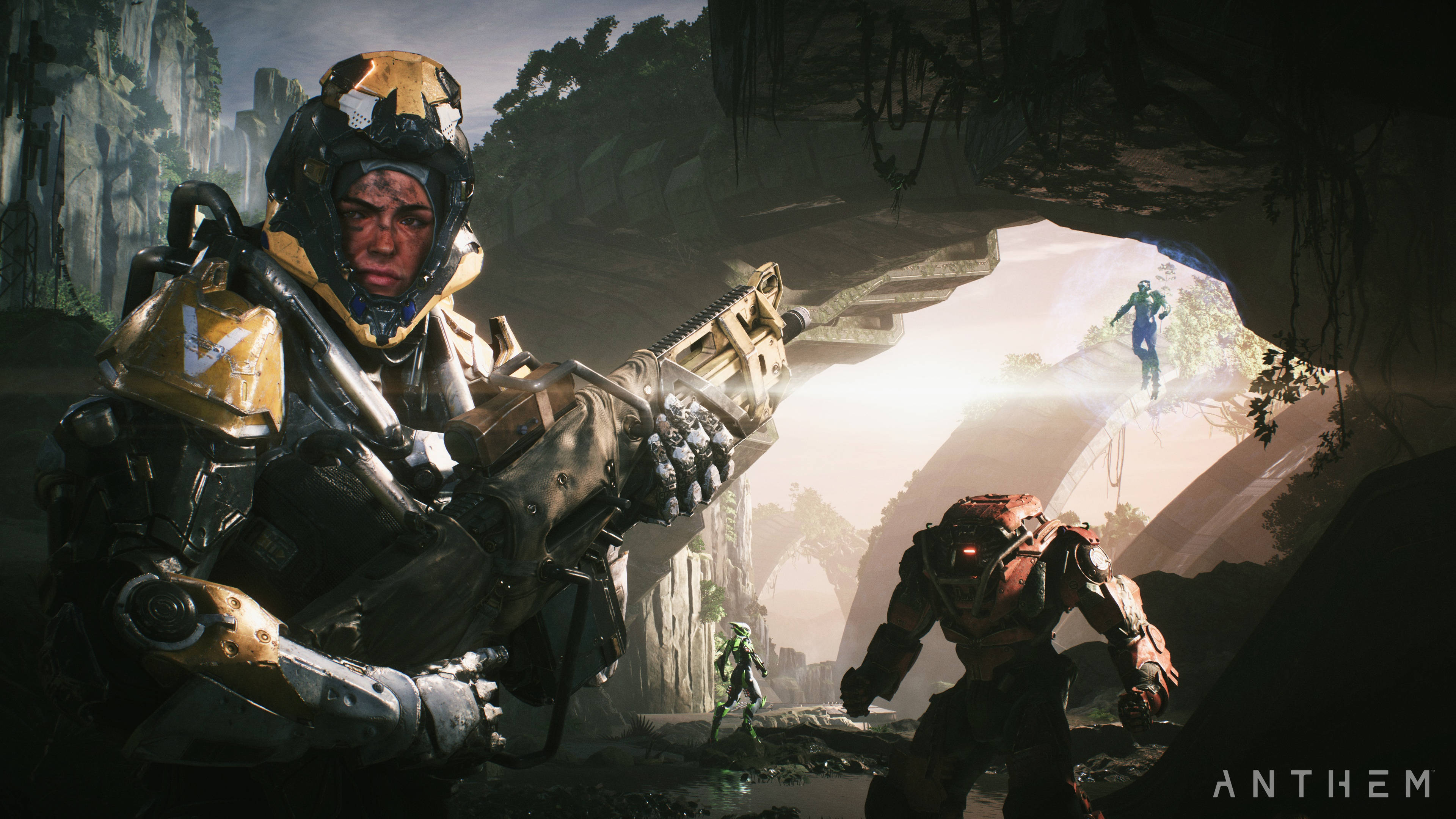 Anthem 4K 裝甲戰士 壁紙 — 一名身穿重甲、戴著金色頭盔並手持武器的士兵站在黑暗的洞穴中，陽光從開口處射入，顯露出崎嶇峽谷景觀中的其他裝甲人物。