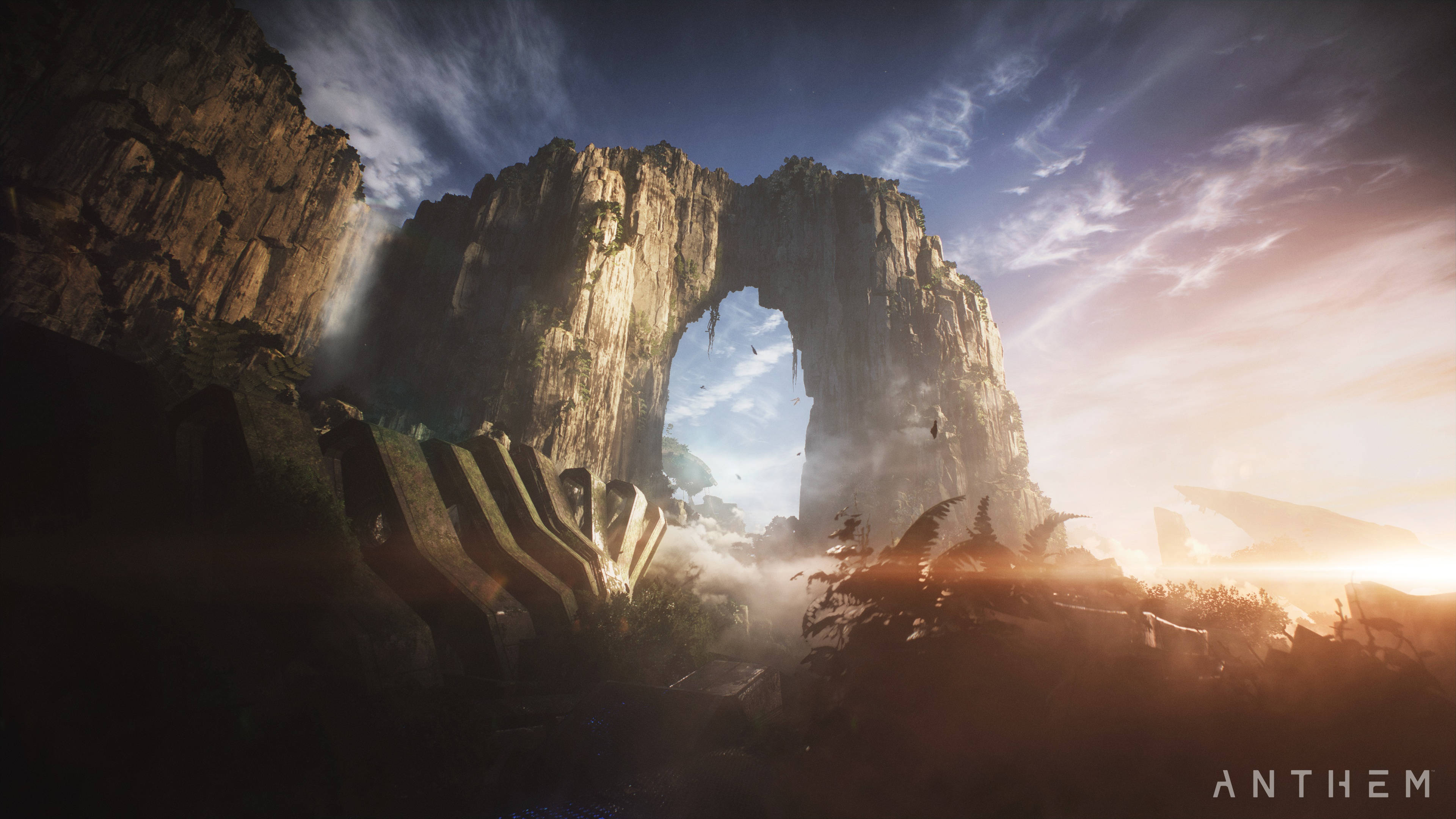 Anthem 4K 岩石拱門 壁紙 — 一座雄偉的石拱門聳立在日落時分的霧氣山谷之上，溫暖的光線在崎嶇的懸崖和古代遺蹟上投下長長的陰影。