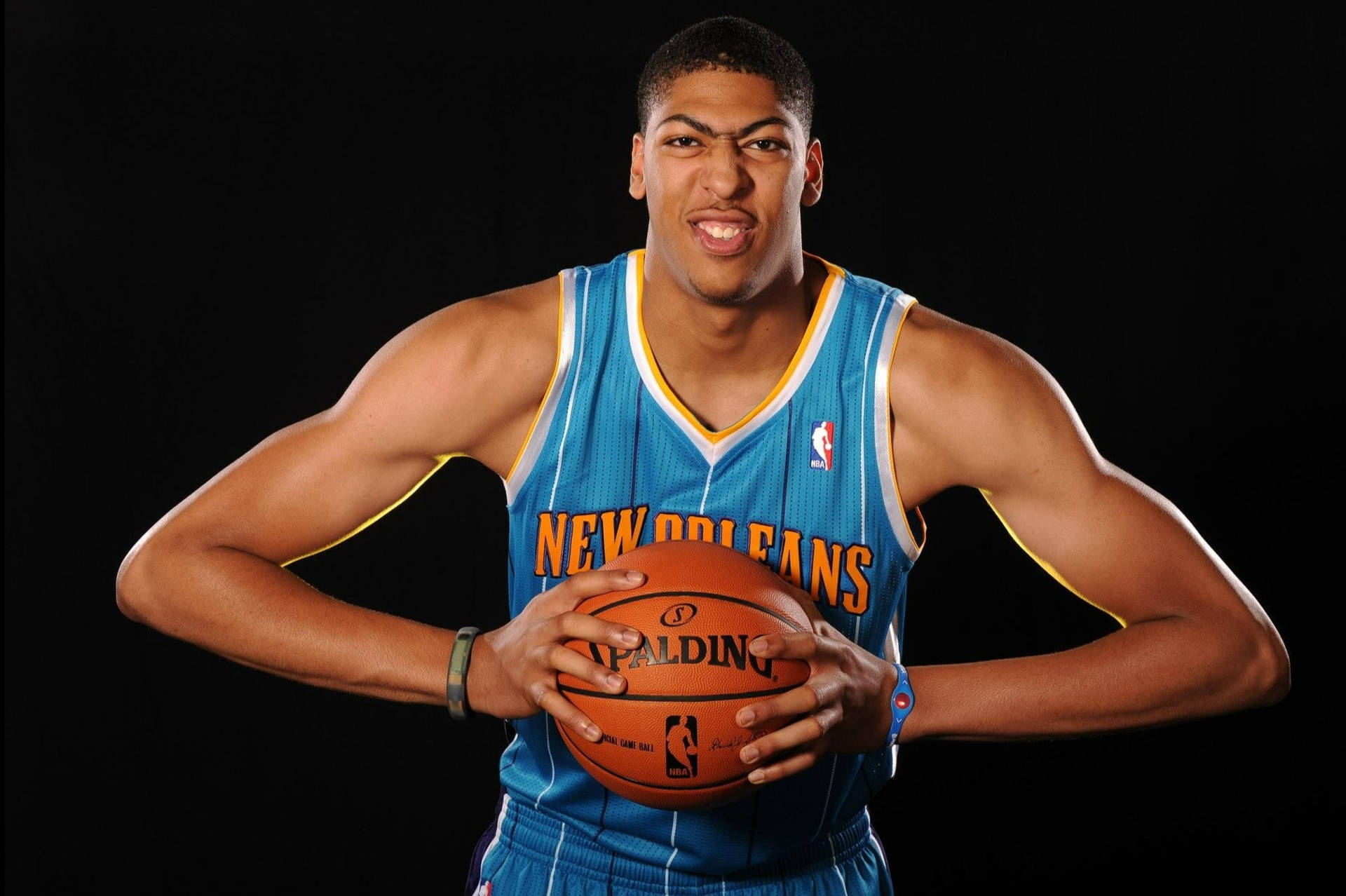 身穿新奧爾良球衣的籃球運動員拿著 Spalding 球微笑。