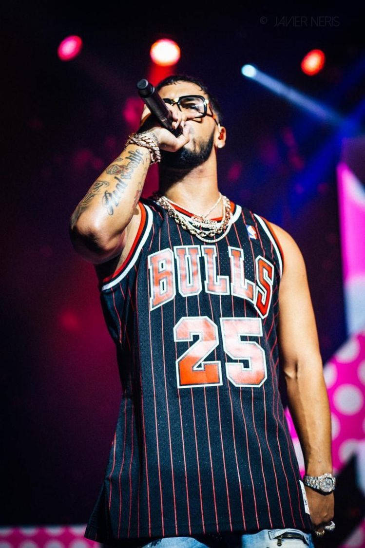 Anuel AA 嘻哈演唱會 壁紙 — 一位穿著Bulls 25球衣的饒舌歌手在彩色舞台燈光下表演，身上有紋身和鏈條。