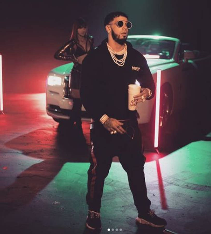 Anuel AA 與 Cosculluela 壁紙 — 一位戴著太陽眼鏡和鏈條的時尚男士自信地站在一輛豪華汽車旁，背景是霓虹紅綠燈光，還有一位女士。