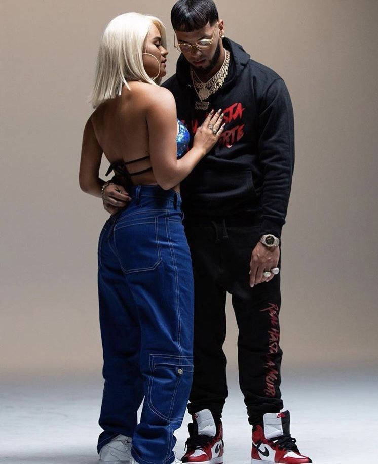 Anuel AA 與 Karol G 照片拍攝 壁紙 — 一對時尚情侶在工作室中以中性色調和大膽街頭服飾時尚親密擺姿勢。