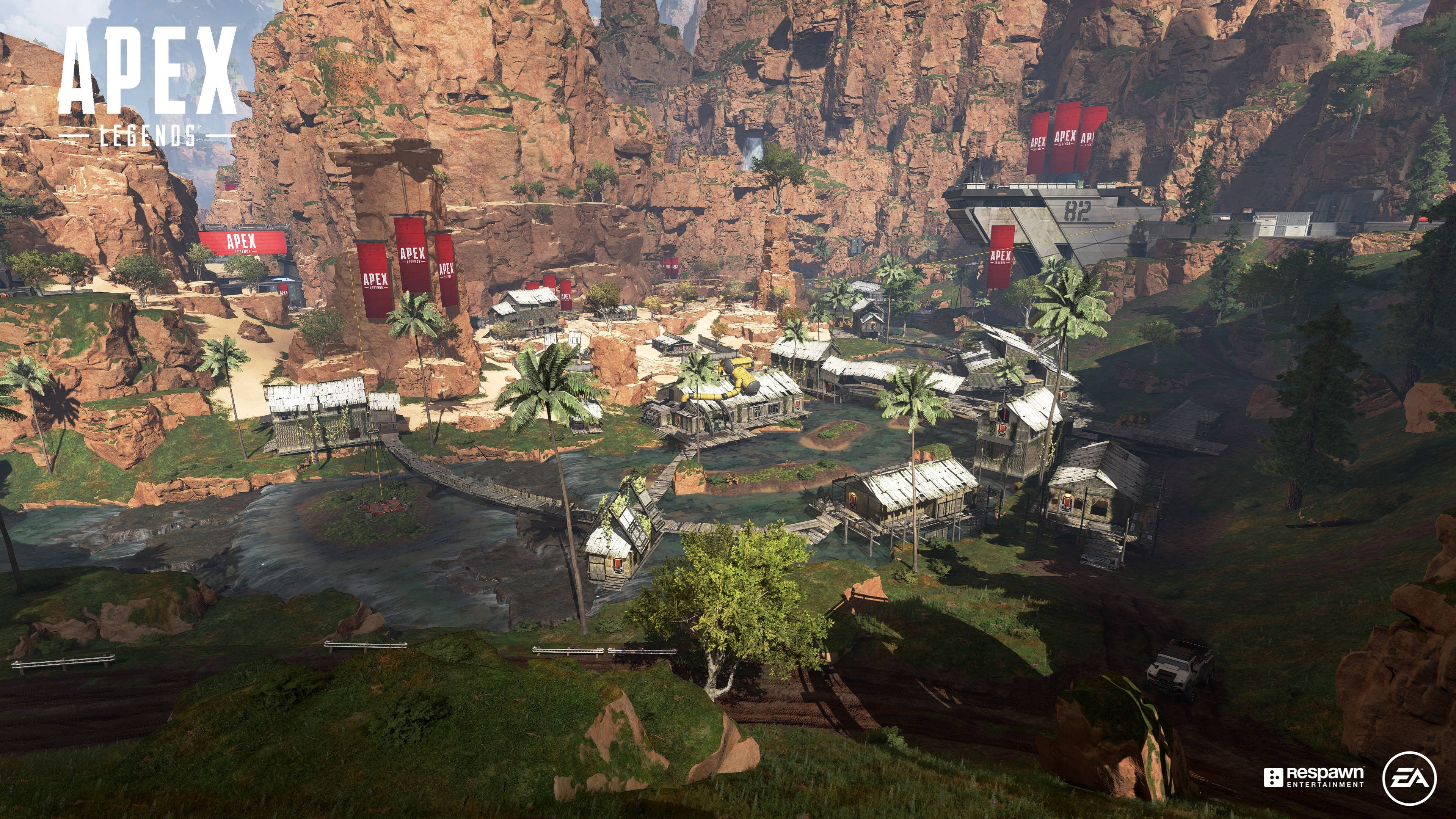 Apex Legends 4K 河畔房屋 壁紙 — 一個充滿活力的遊戲地圖，位於峽谷中，有棕櫚樹、河流和紅色旗幟，在明亮的日光下。