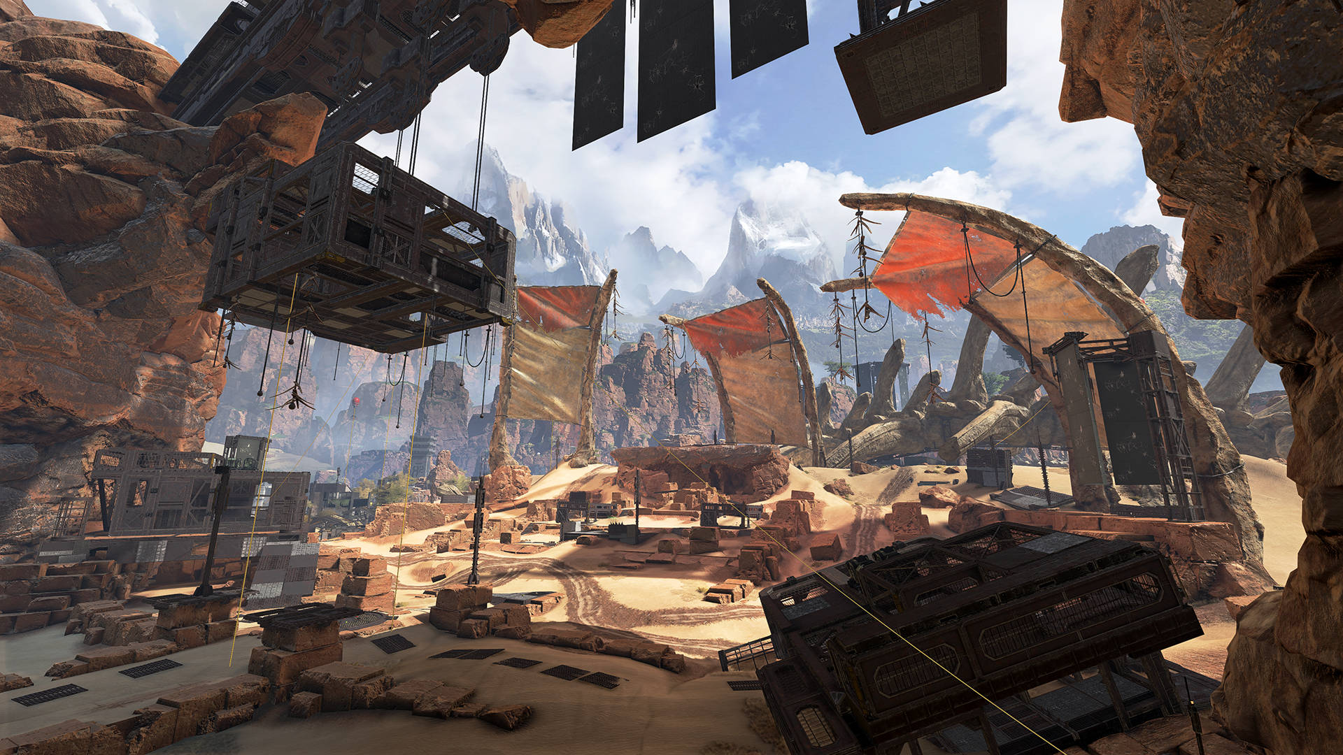 Apex Legends 4K 沙漠工地戰場 壁紙 — 沙漠峽谷中的定居點，有懸掛的平台和破舊的旗幟，在明亮的藍天下，遠處有積雪的山峰。