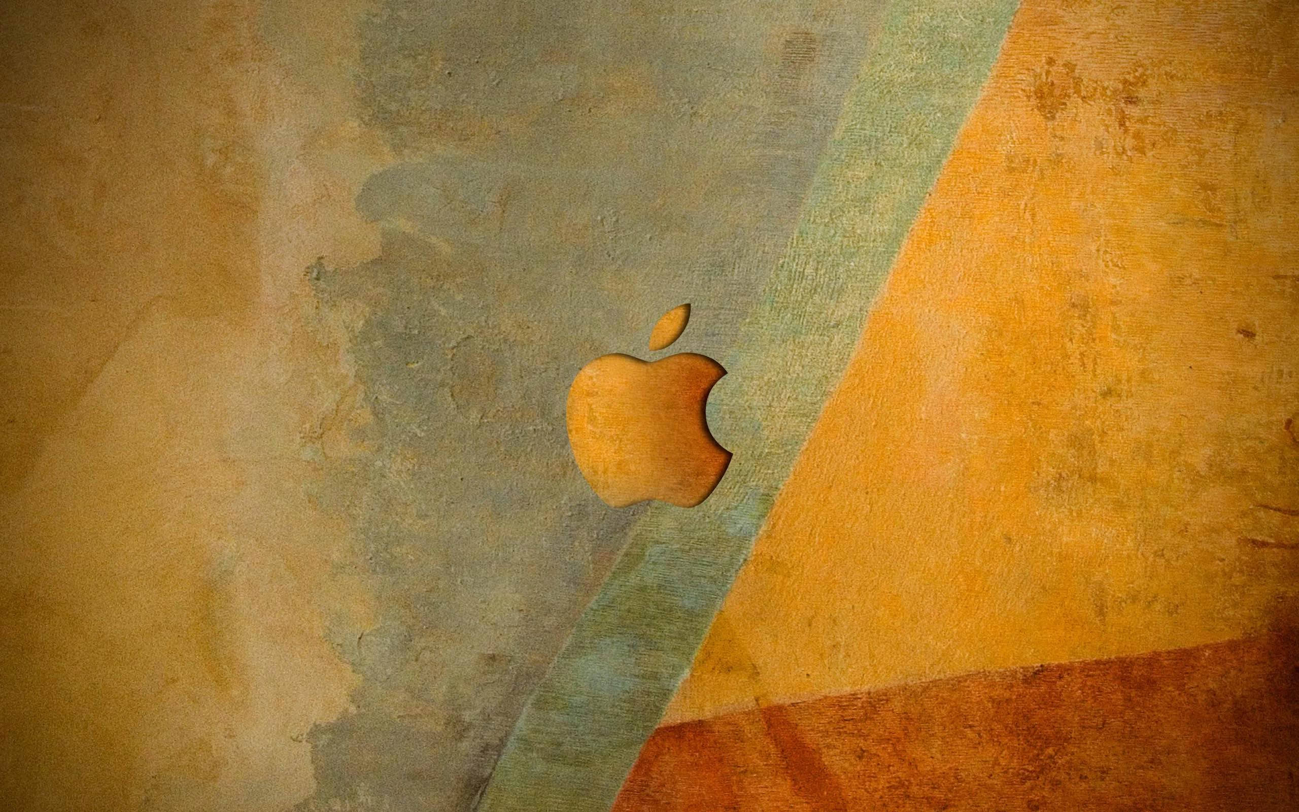 Apple 高清桌面電腦，帶來清晰沉浸式視覺 壁紙 — 一個風化的金色蘋果標誌嵌入在帶有抽象青綠色和赭色幾何部分的紋理牆壁中。