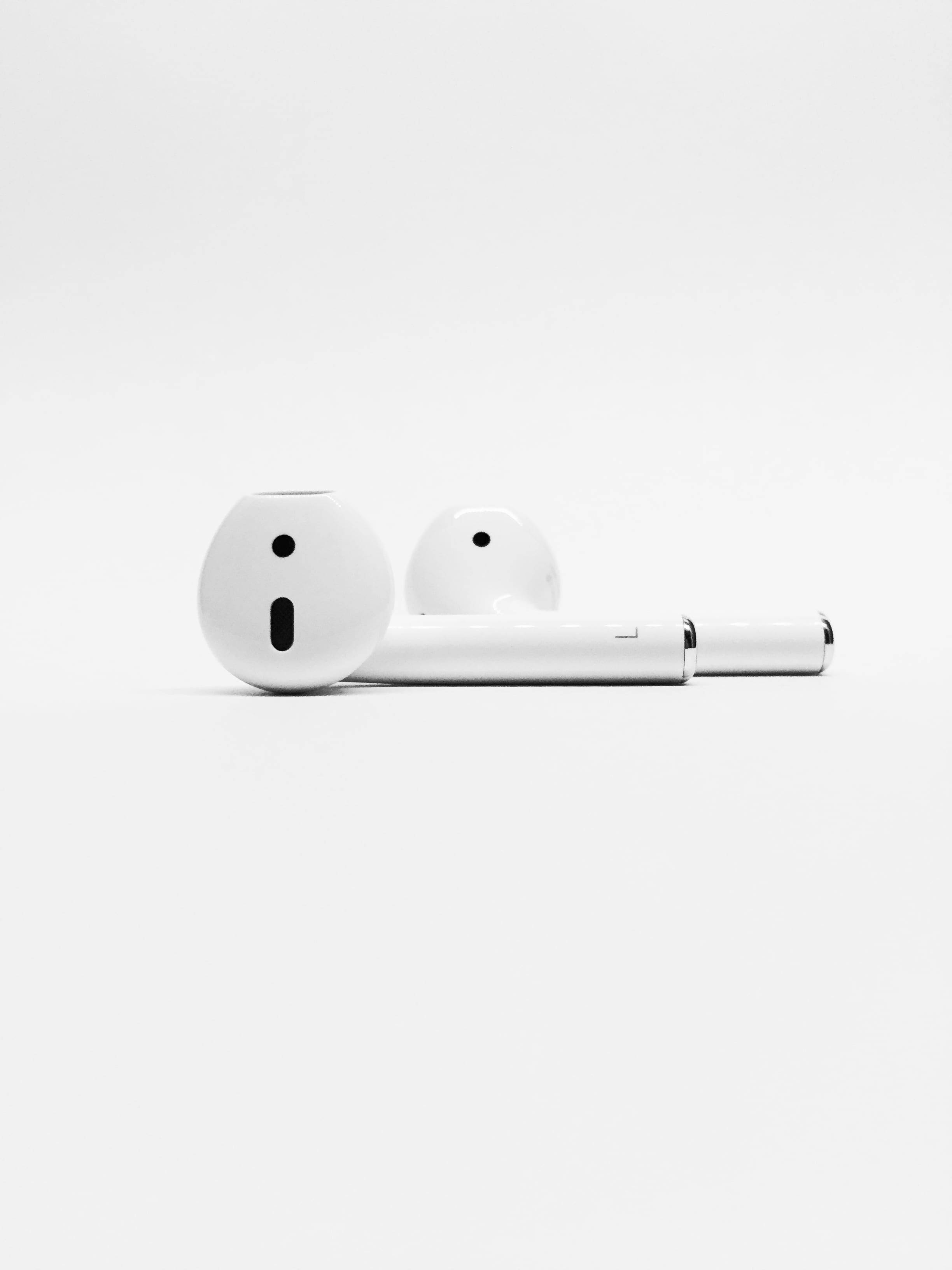 Apple 白色 AirPods 壁紙 — 兩個白色無線耳機及其充電盒整齊地放在純白色背景上。