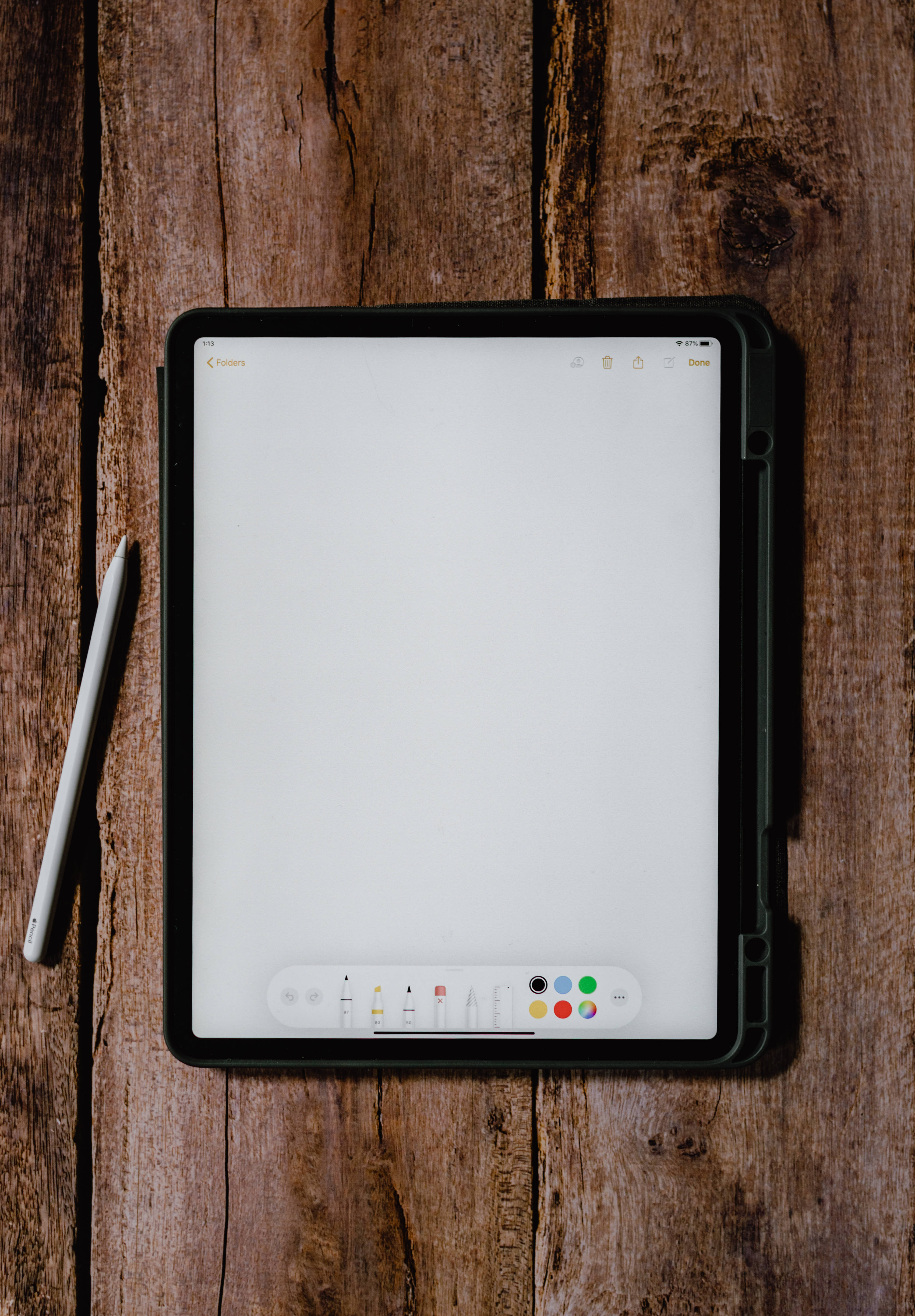 Apple iPad Pro 連繪圖應用程式 壁紙 — 平板電腦連觸控筆放在質樸的木質表面上，顯示空白畫布，準備進行數碼創作。